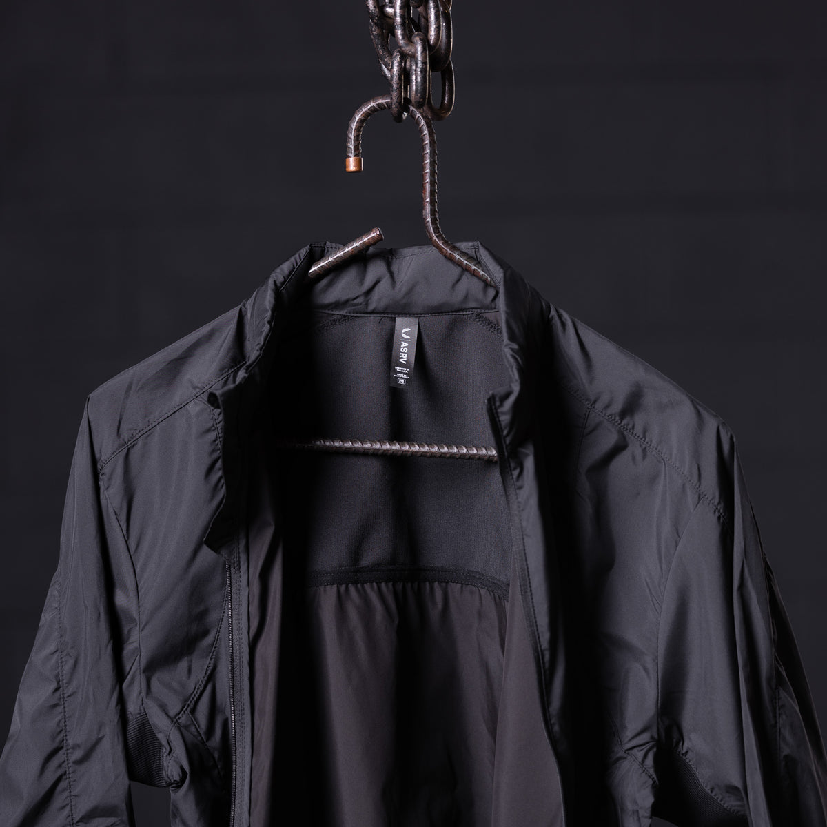 Black lightweight windbreaker on hanger, front open view showing interior lining and label
