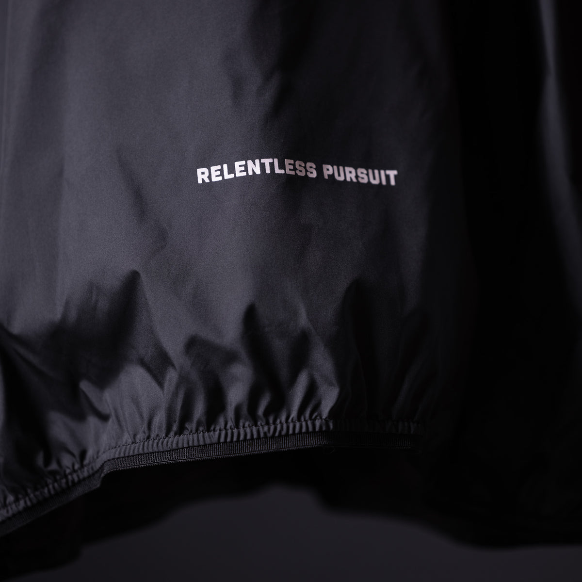 SP'23 Waterproof Jacket in black, detail shot of 'Relentless Pursuit' text and elastic cuff