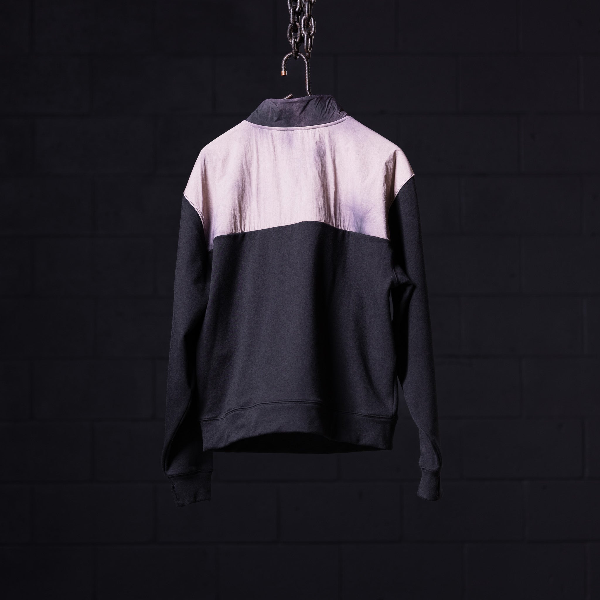 WN'23 Panel Quarter Zip Jacket in black and mauve, hung on chain against dark background
