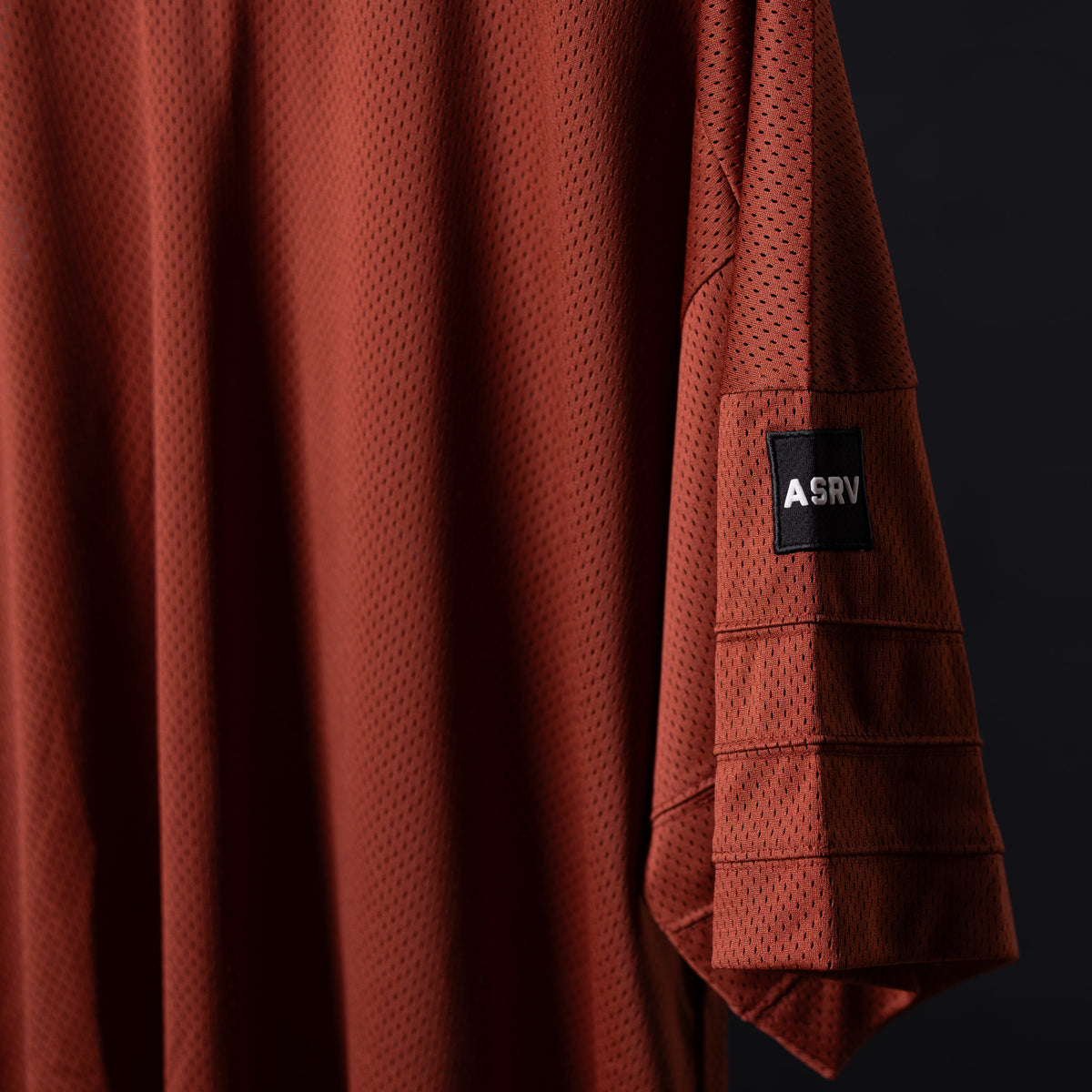 SM'23 Mesh Oversized Jersey in rust red, draped detail shot showing fabric texture and ASRV label