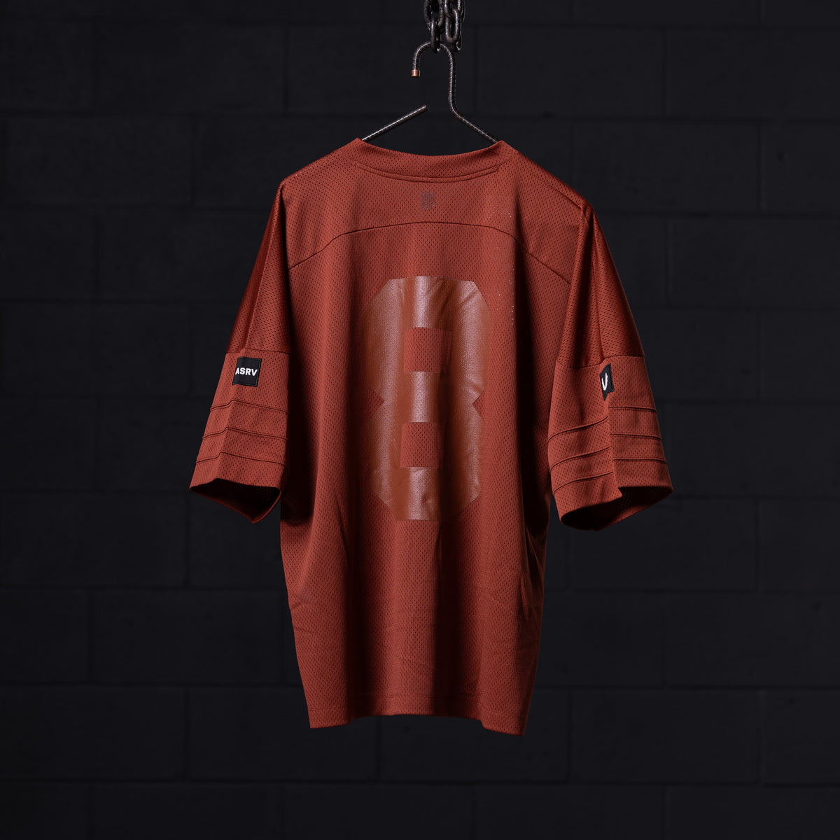 SM'23 Mesh Oversized Jersey in rust red, displayed on hanger against dark background
