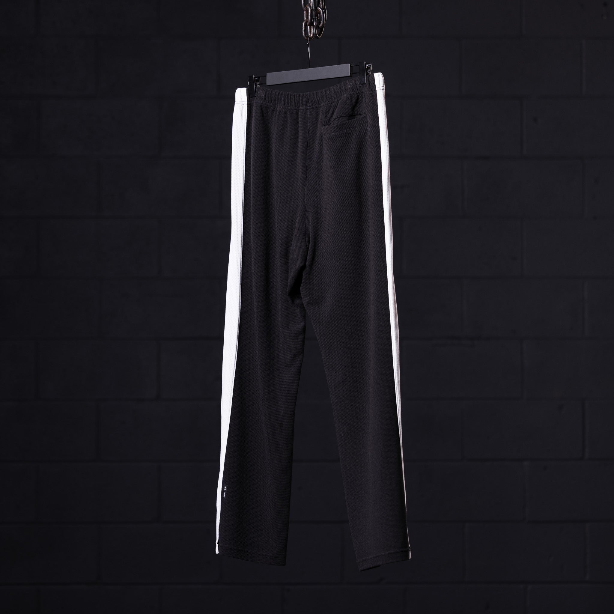 SM'24 Waffle Knit Sweat Pant in black with white side stripes, hanging on hanger
