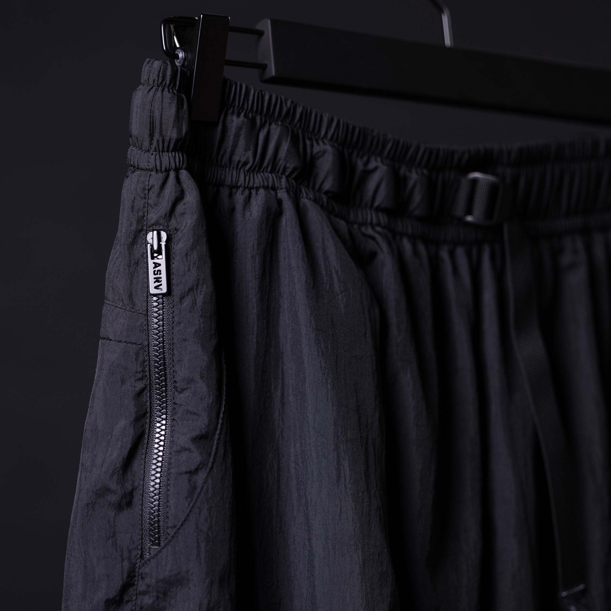 2021 Oversized Track Pant in black denim, detail shot of zipper pocket and elastic waistband