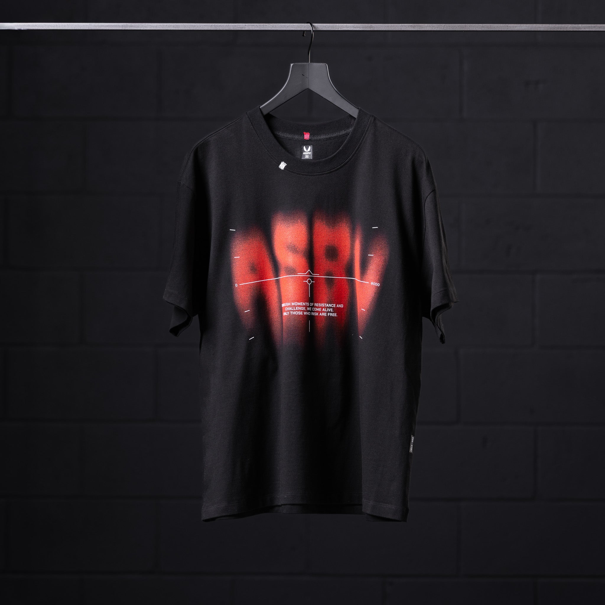 Black Tech Essential Relaxed Tee with red 'Target Acquired' graphic, displayed on hanger