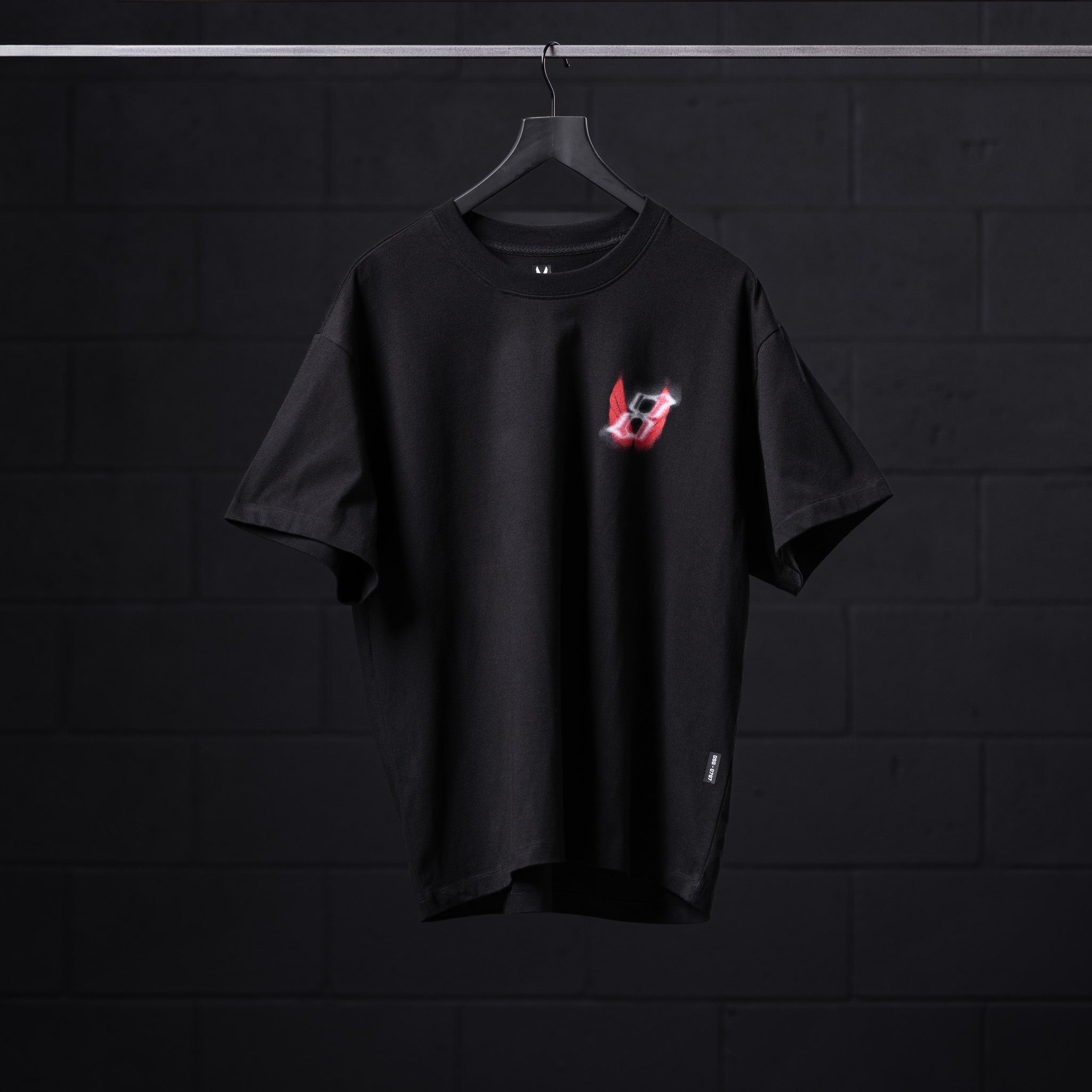 Black Tech Essential Relaxed Tee with red neon 'Infinite Mindset' graphic, displayed on hanger