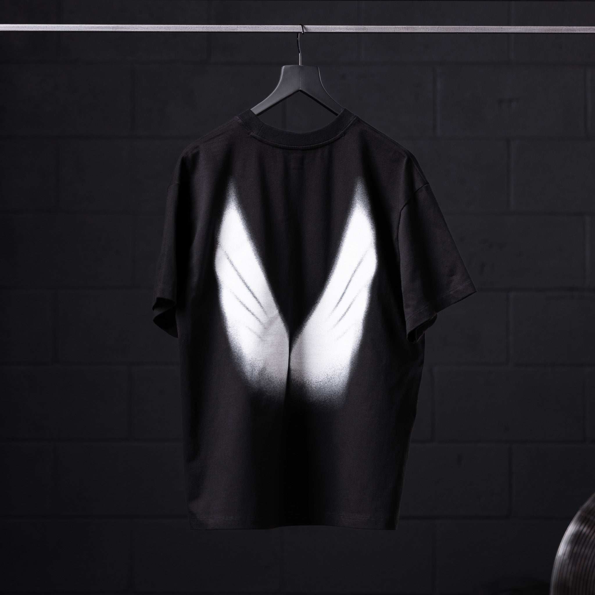 Black Tech Essential Relaxed Tee with white graphic design, back view on hanger