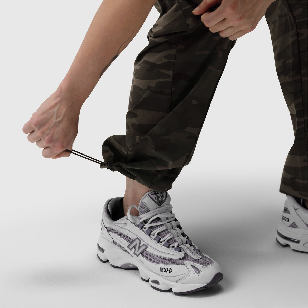 Dark camo ripstop relaxed track pant worn with white sneakers, front view