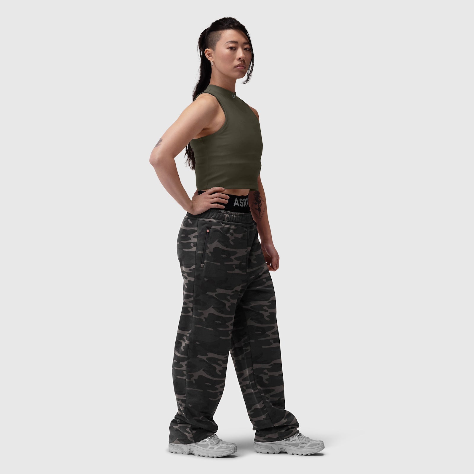 Olive ribbed mockneck tank worn with black camo cargo pants, side view