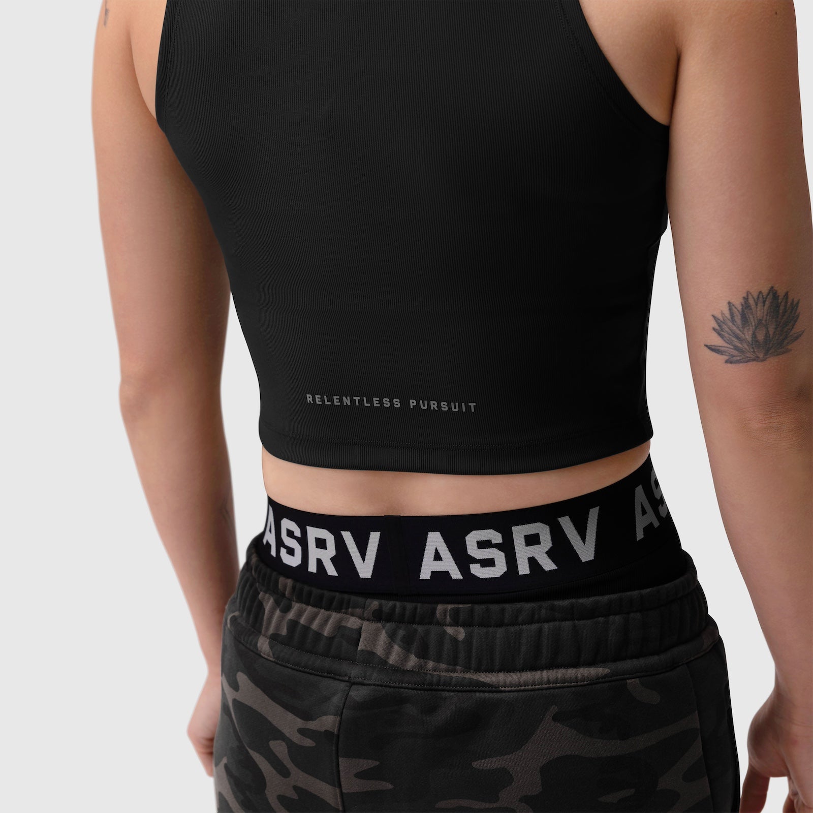 Black ribbed mockneck tank worn with camo shorts, front view on model with lotus tattoo