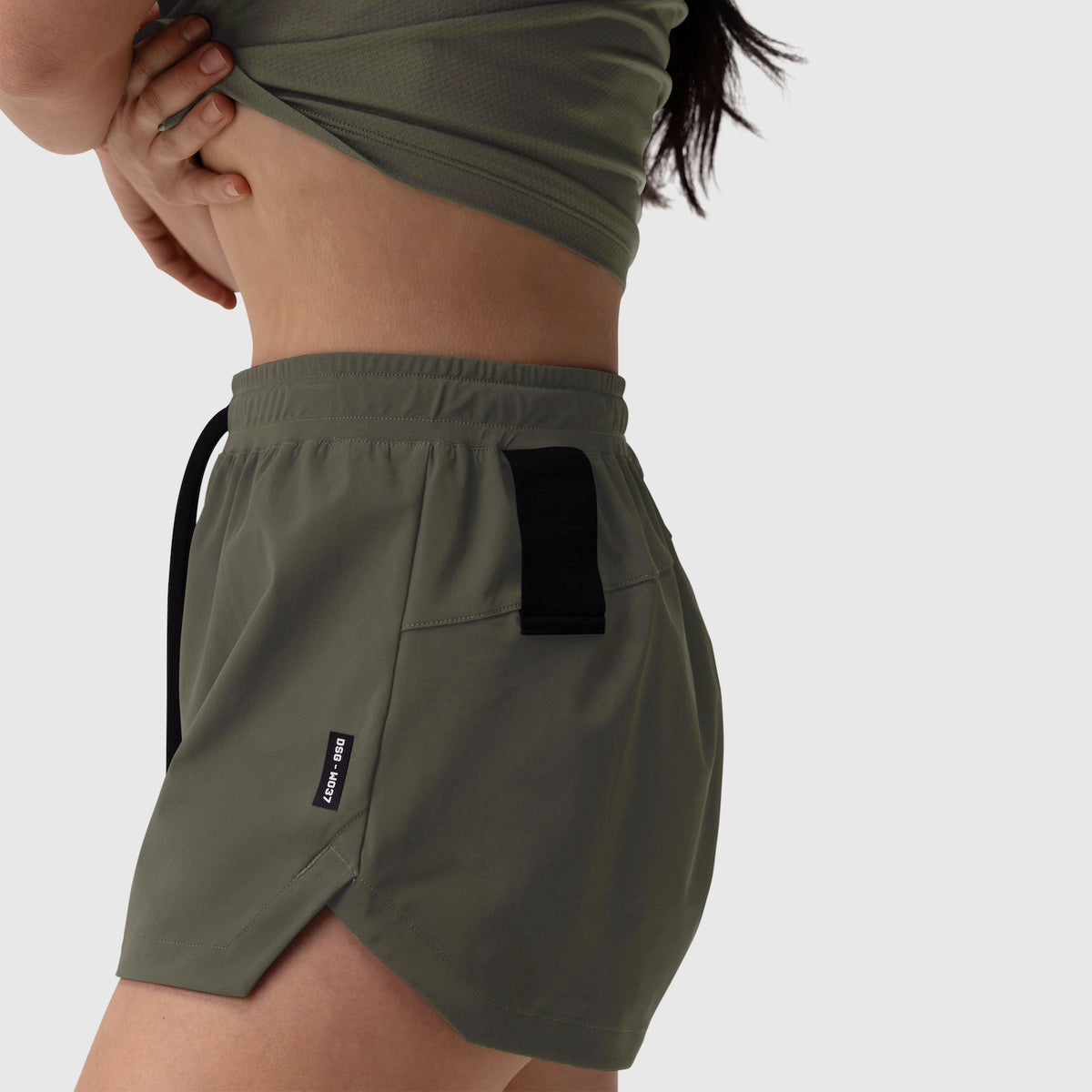 Tetra-Lite Linerless Short in olive worn by model, side view showing pockets