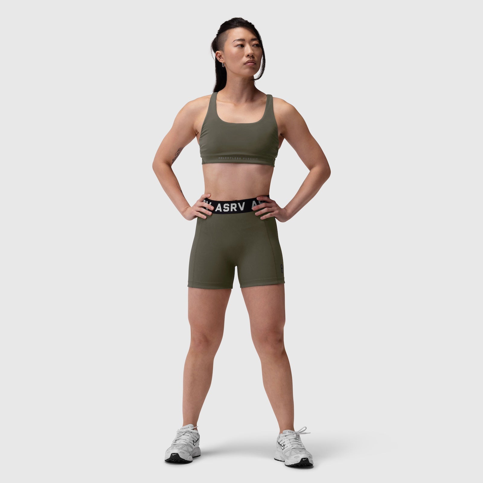 LYCRA® Hybrid Sports Bra in olive, worn by model standing facing forward with hands on hips