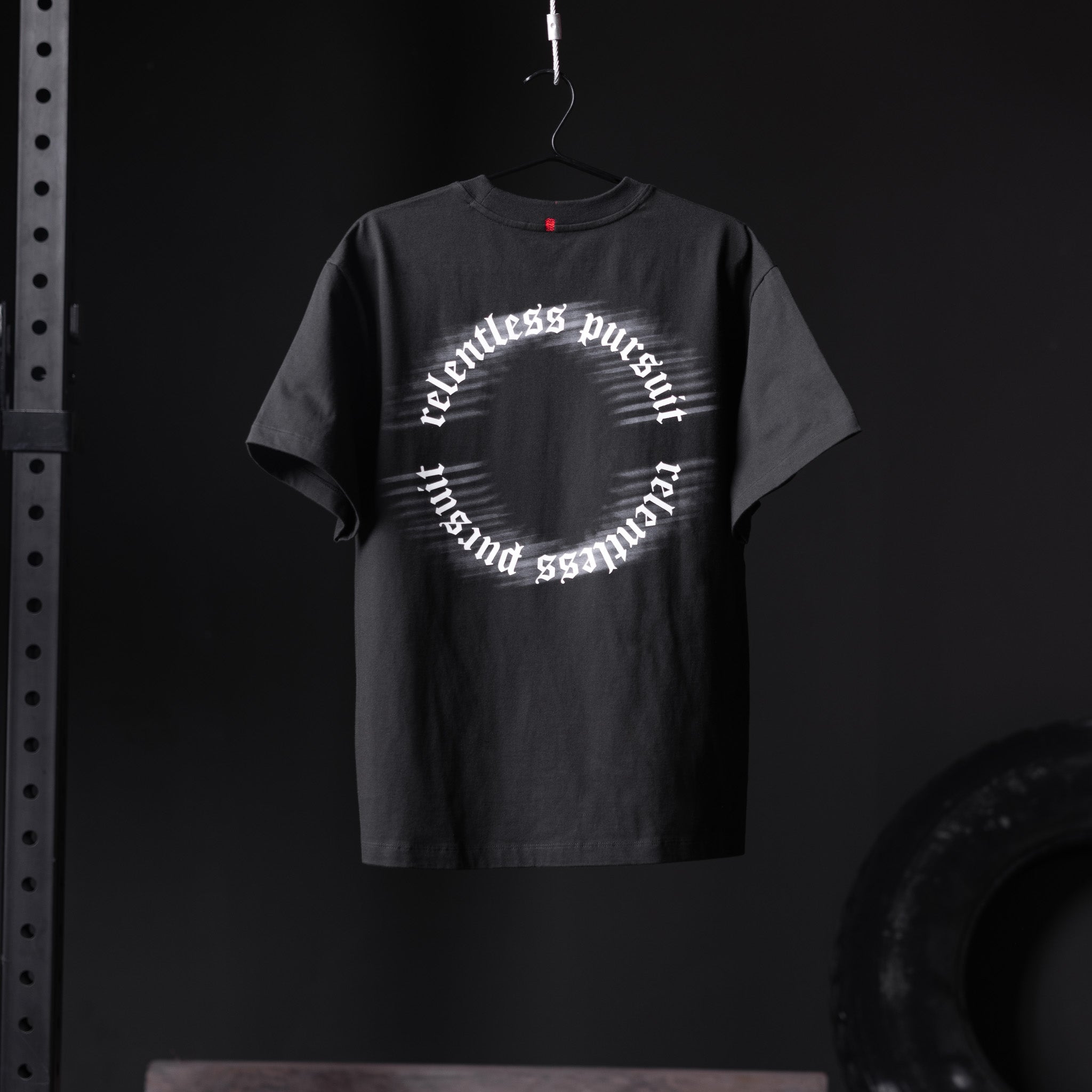 Black Tech Essential Relaxed Tee with 'RP Blur' circular text design, hanging on hanger