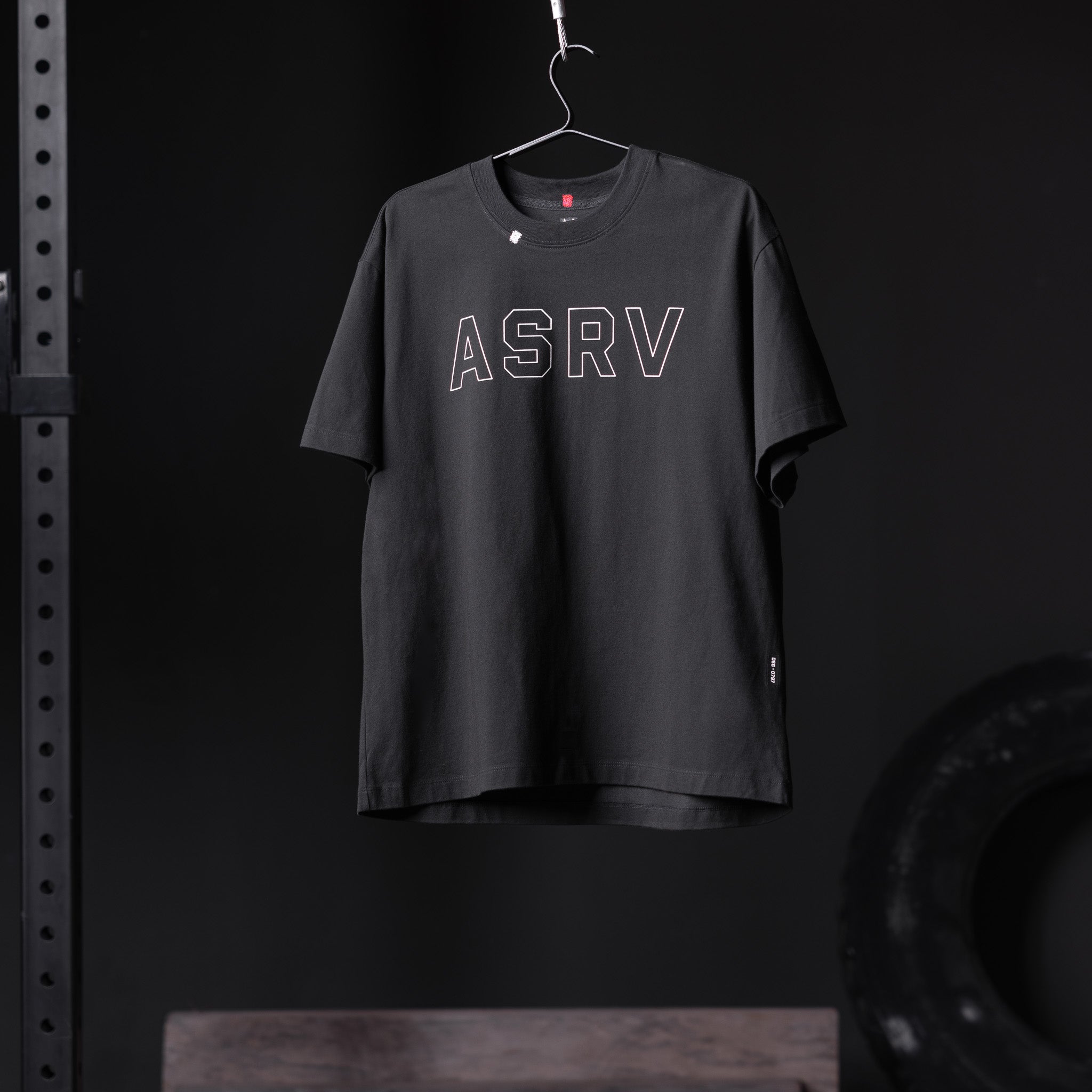 ASRV Tech Essential Relaxed Tee in black with outline logo, displayed on hanger