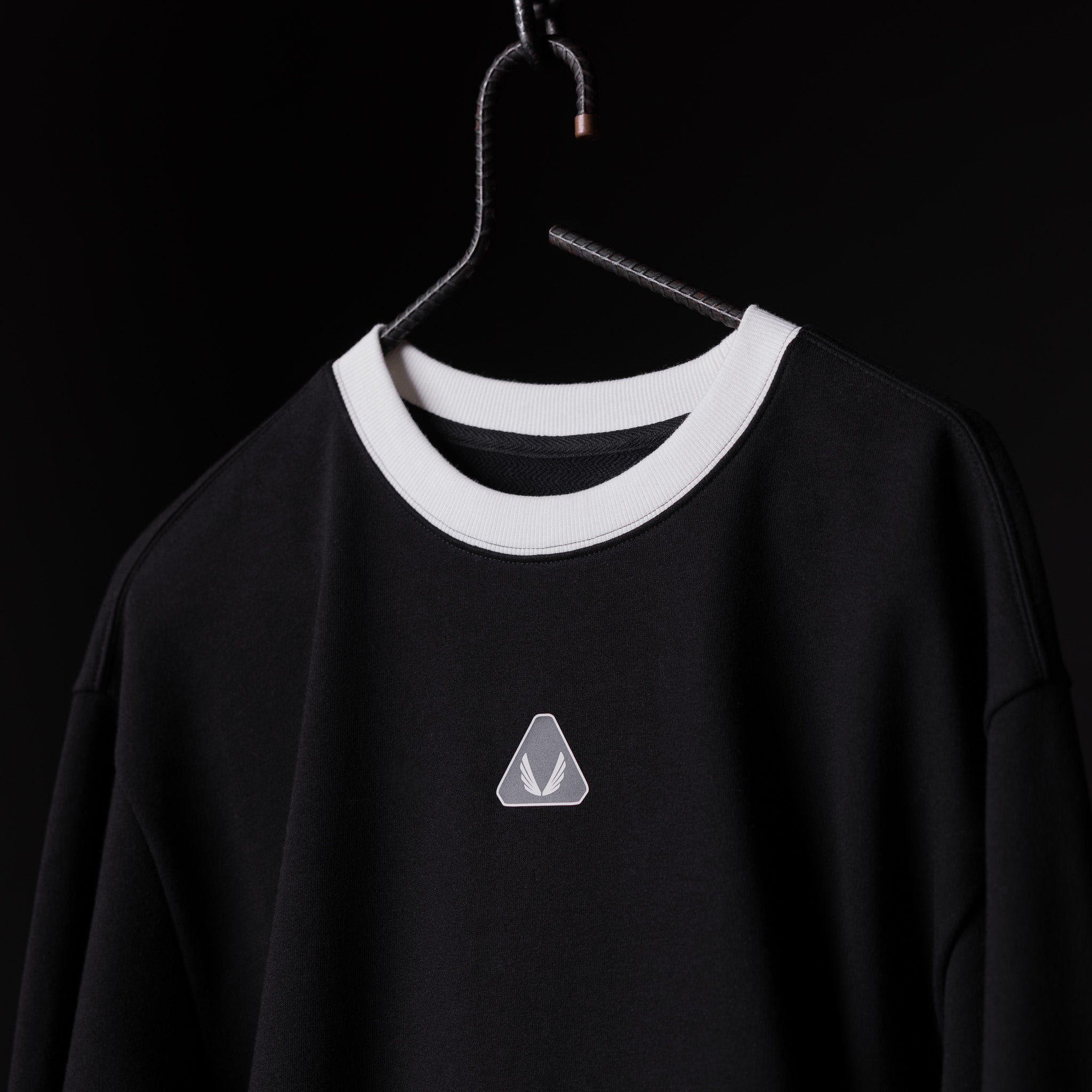 Black Terry Crew Neck sweatshirt with white ribbed neckline on hanger against black background