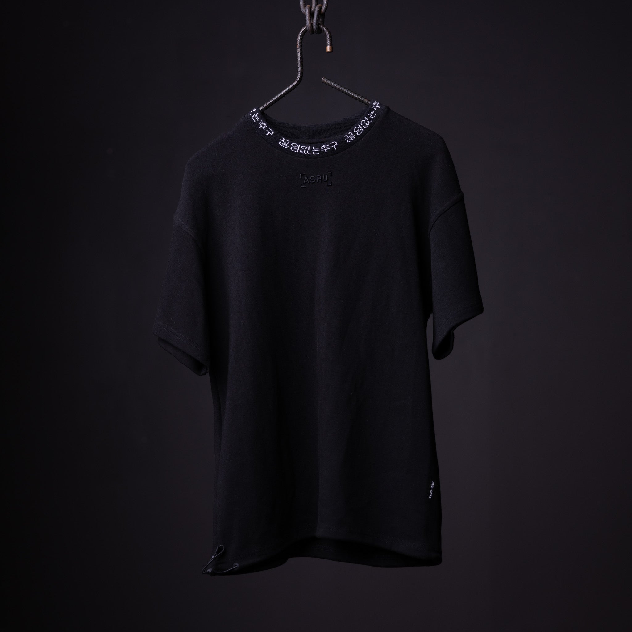 Black oversized cinch tee on hanger with decorative chain neckline detail, front view