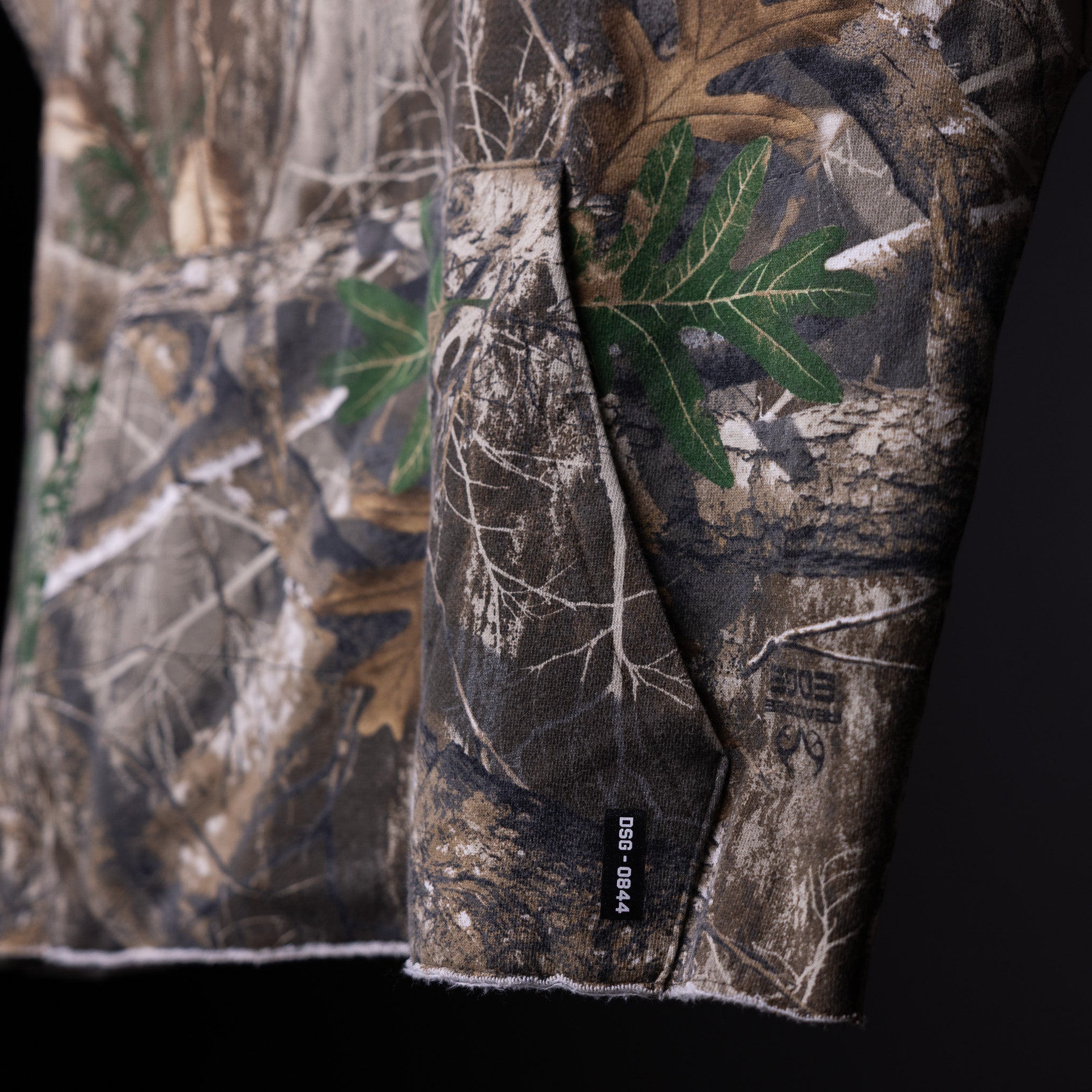 Raw hem cutoff hoodie in camouflage pattern, detail shot of sleeve and fabric texture