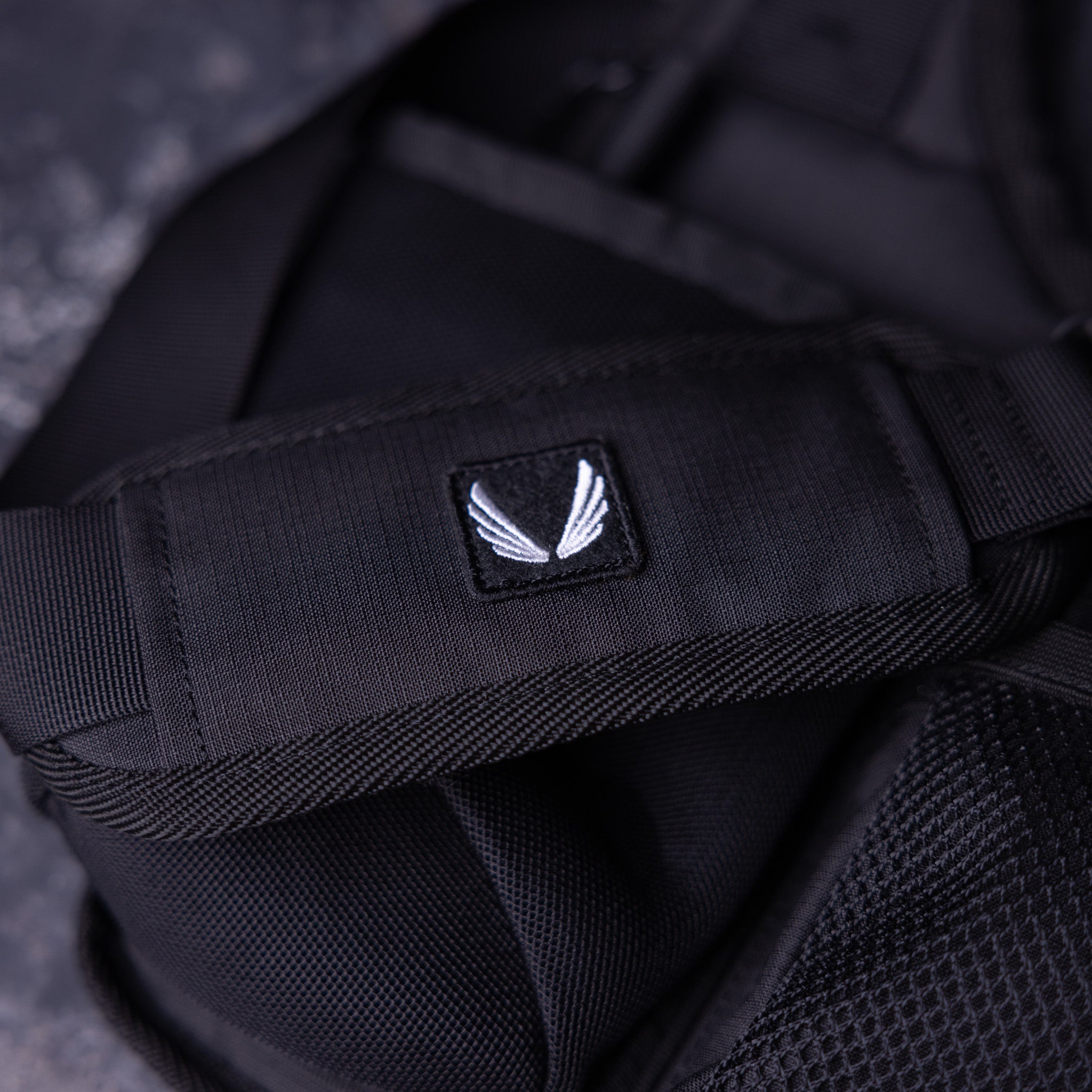 SM'23 Crossbody in black, close-up detail of logo patch
