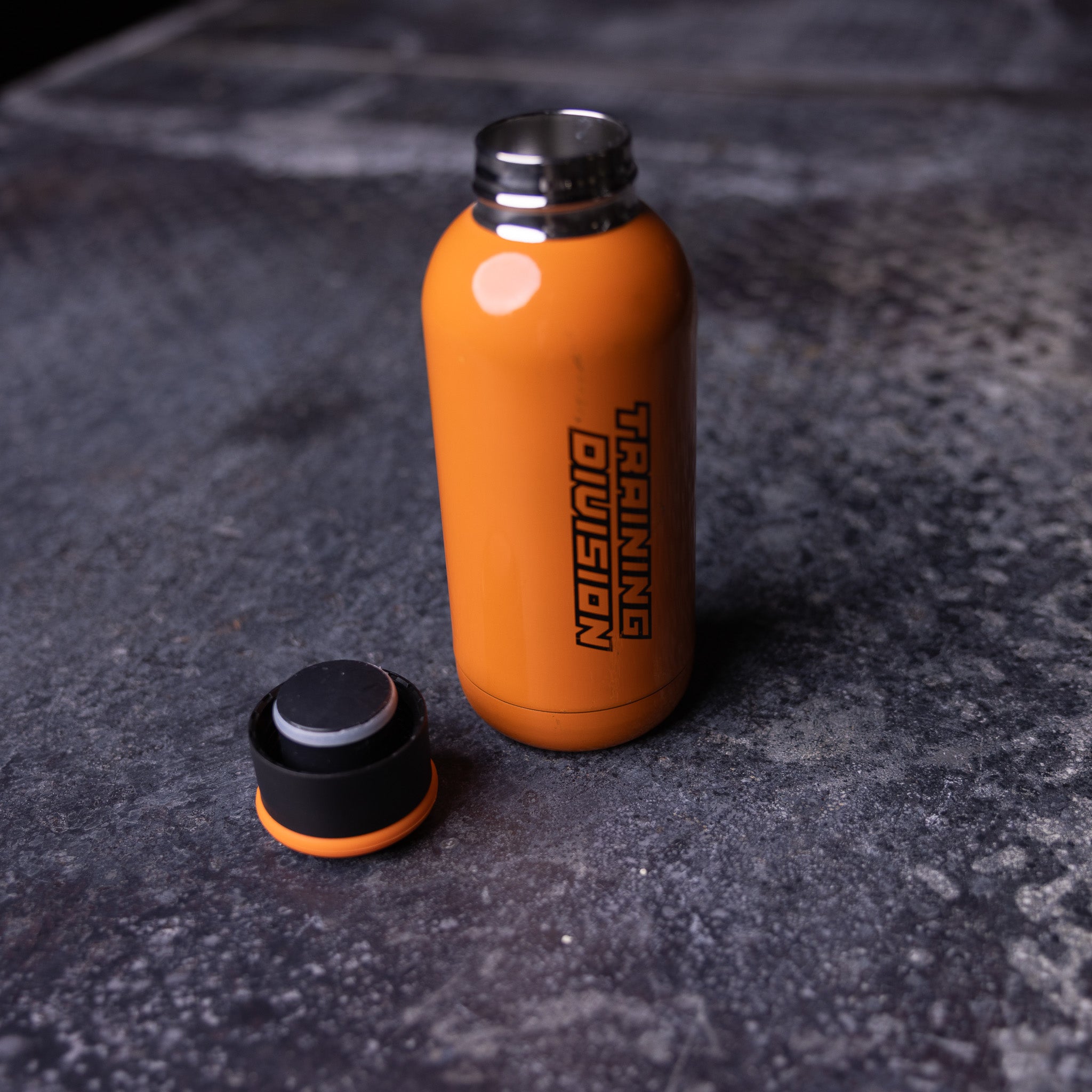 of ASRV Training Division water bottle in orange with black cap, shot from above on concrete surface