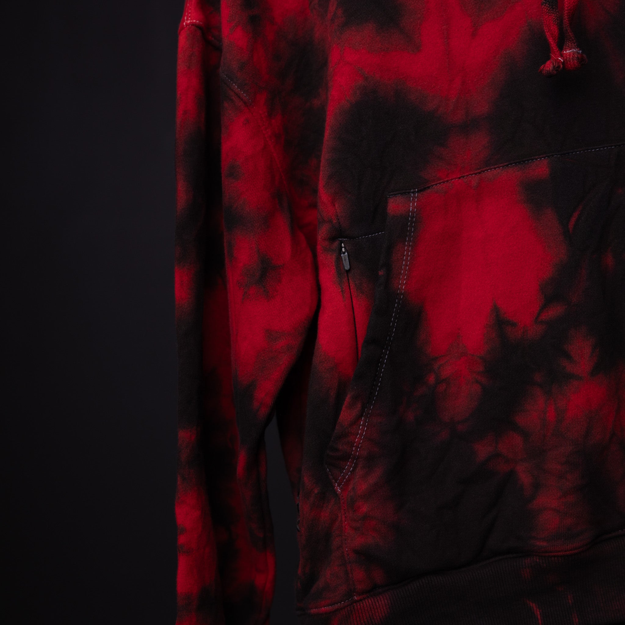 SM'22 Tie Dye Hoodie in red and black tie dye, worn on model showing front detail and pocket