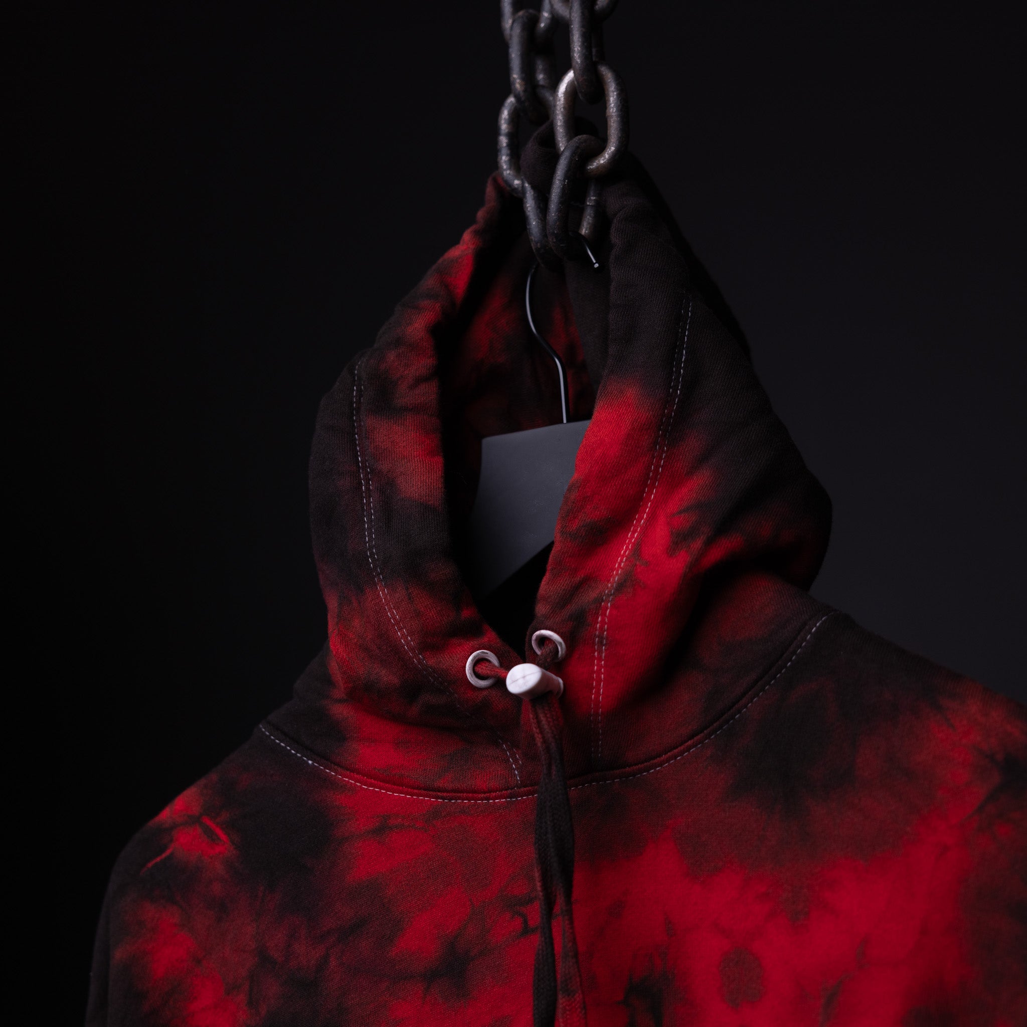 SM'22 Tie Dye Hoodie in red and black tie dye, displayed on model against dark background