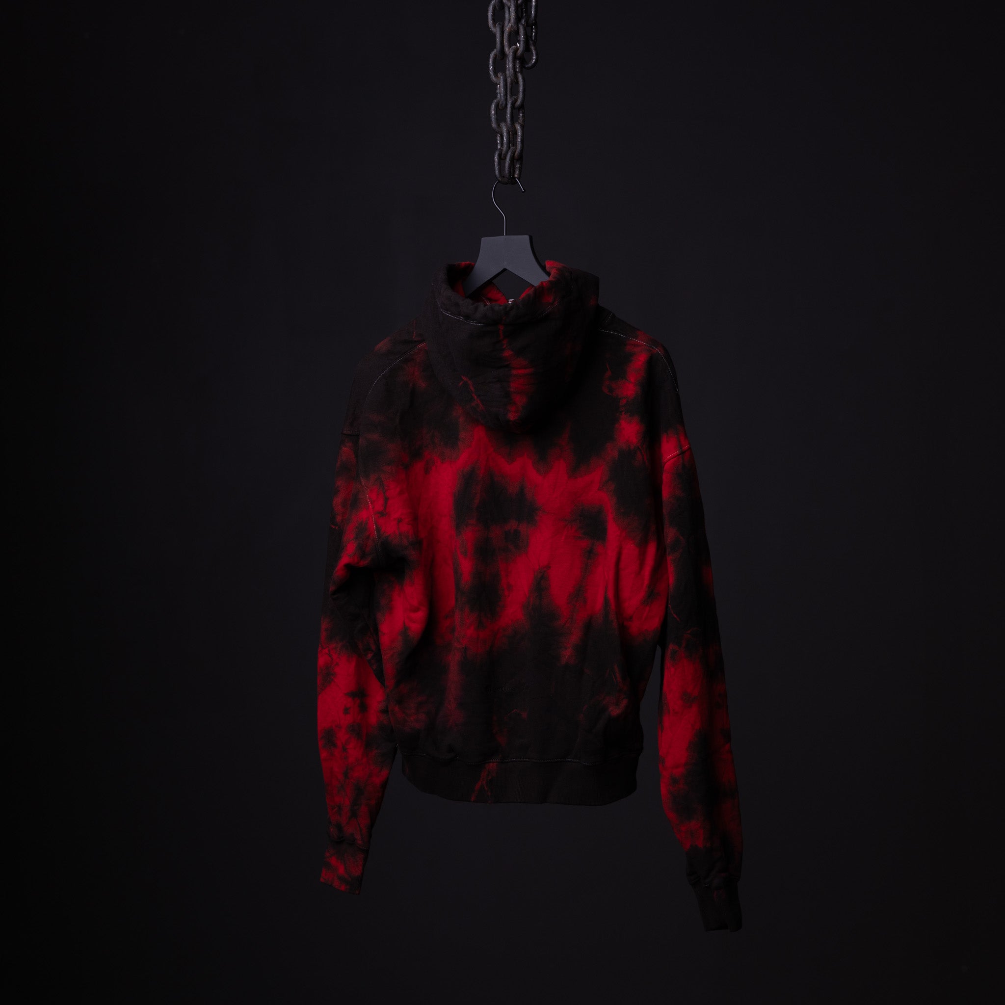 SM'22 Tie Dye Hoodie in red and black tie dye, displayed on hanger against dark background
