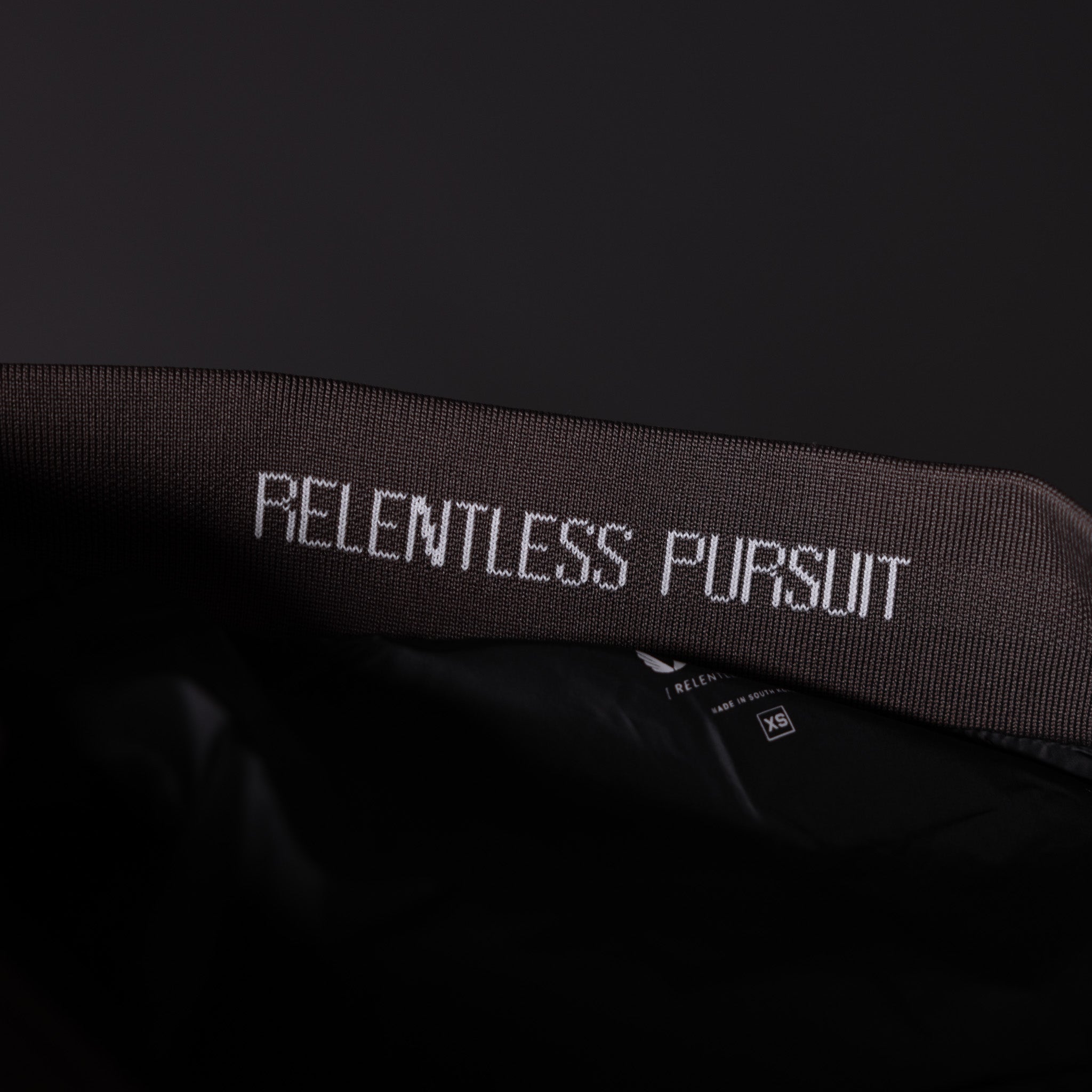 SP'23 Waterproof Run Vest in black, detail shot of neck label with 'Relentless Pursuit' text