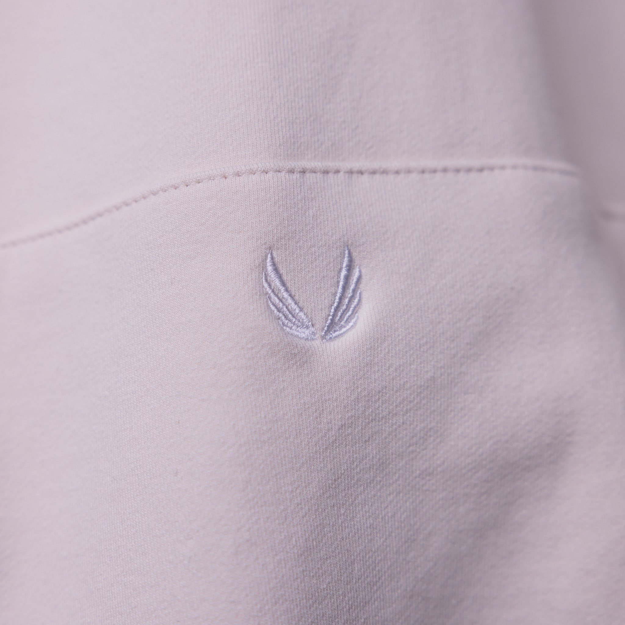 Tech Terry Eagle Hoodie detail closeup showing embroidered wing logo on light purple fabric