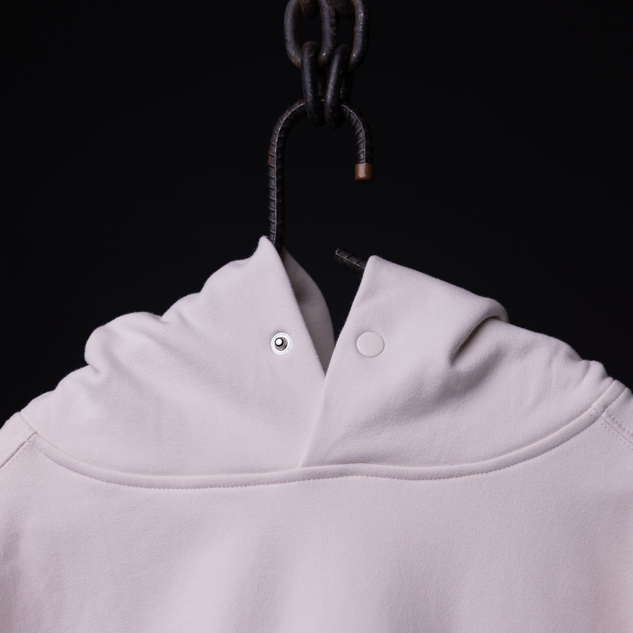 Tech Terry Eagle Hoodie in white, hung on dark hook showing collar detail