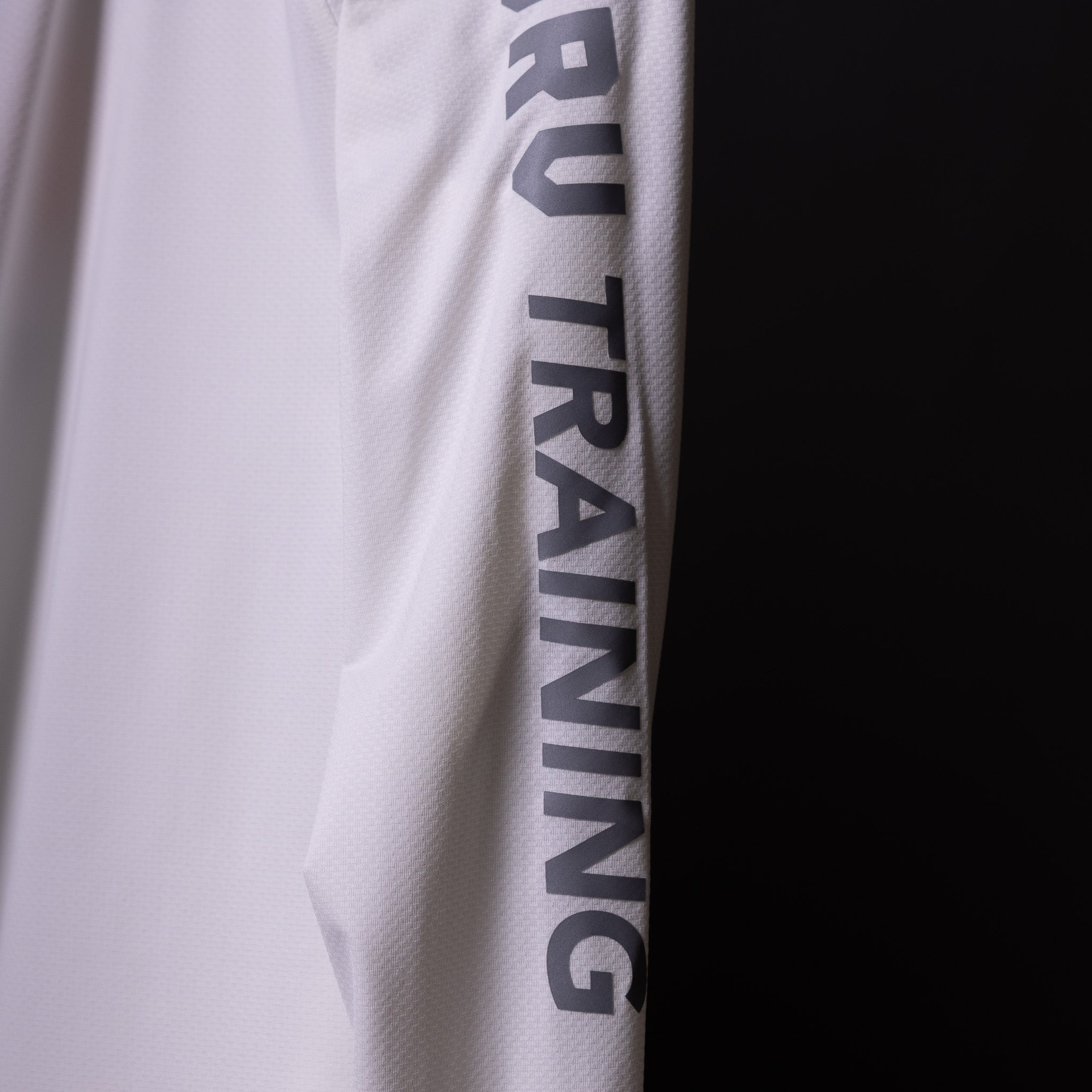 SP'20 Long Sleeve Shirt in white, sleeve detail closeup showing 'RUN TRAINING' text