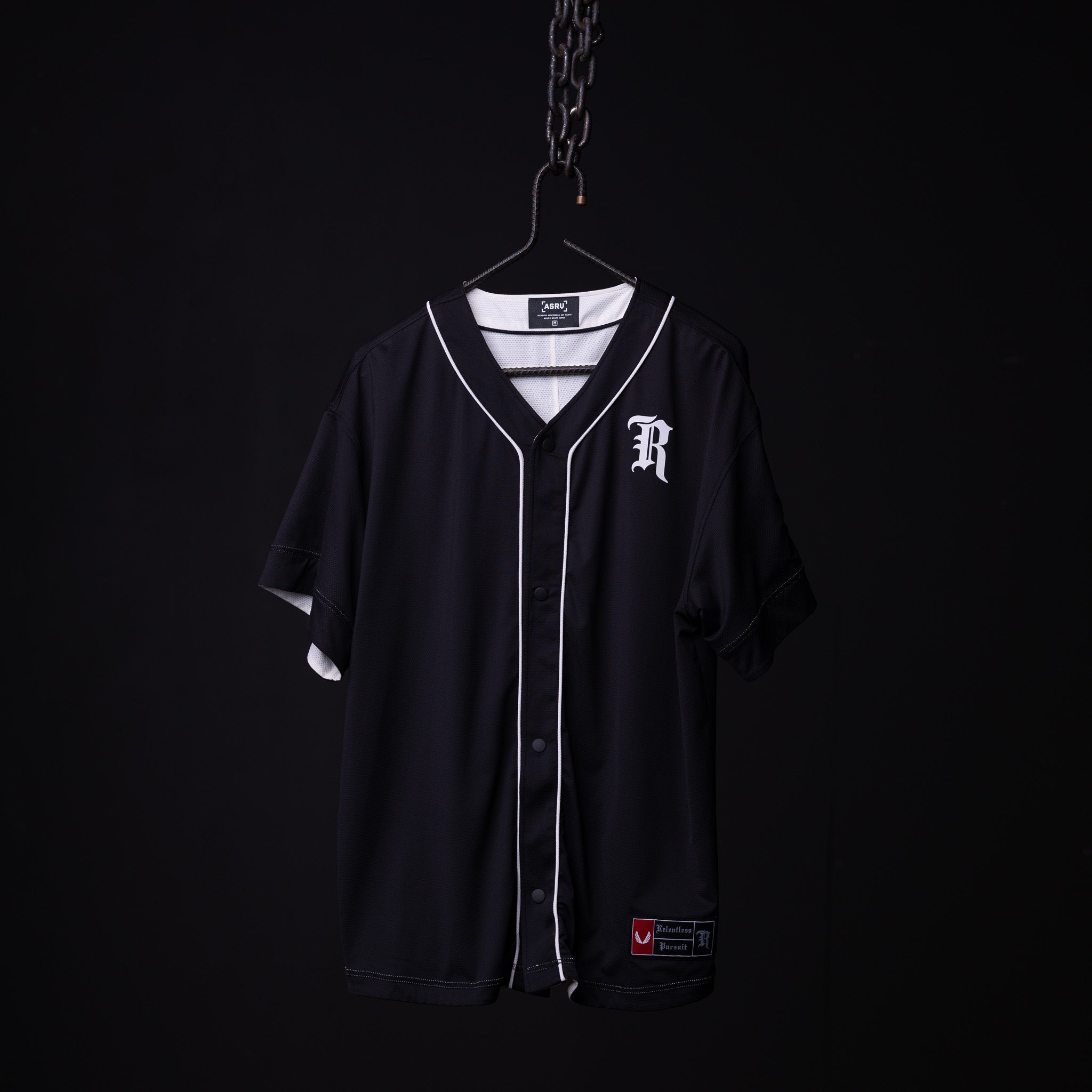 FA'21 Reversible Jersey in black with white piping on hanger against dark background