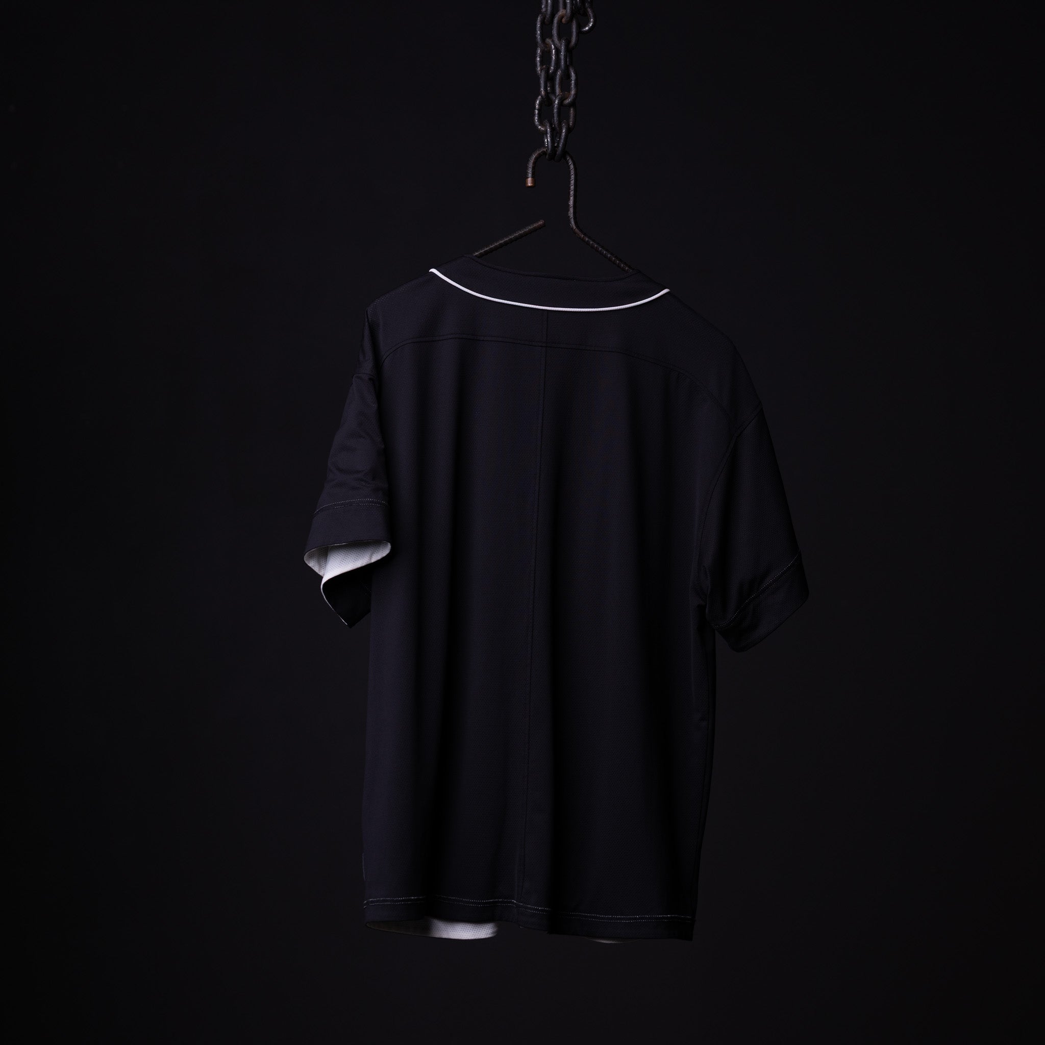 FA'21 Reversible Jersey in black on hanger against dark background, back view
