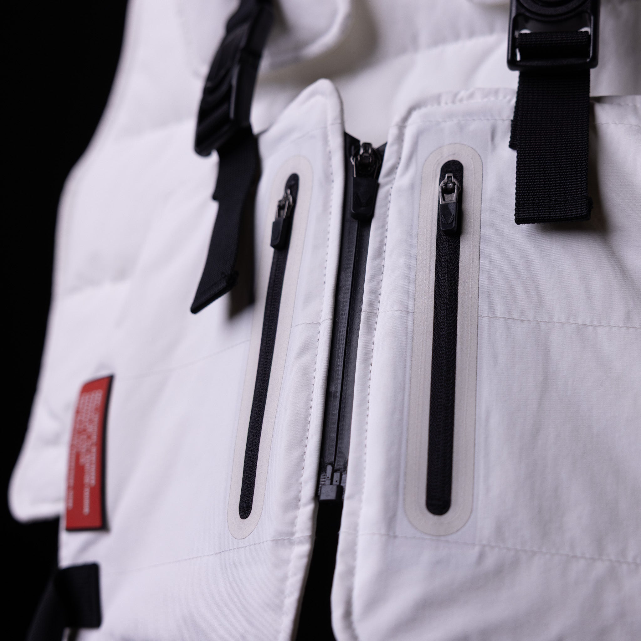 2018 Technical Vest detail closeup showing black zippers and straps on white fabric