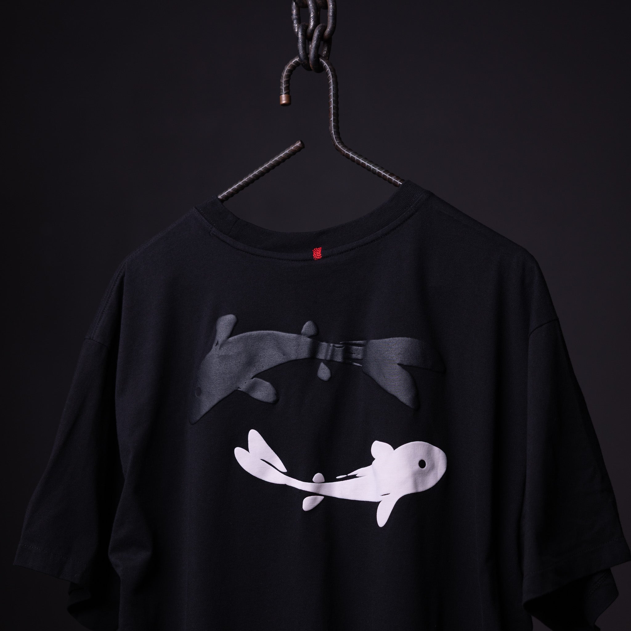SP'23 Graphic Tee in black hanging on hanger, featuring white and gray fish illustration