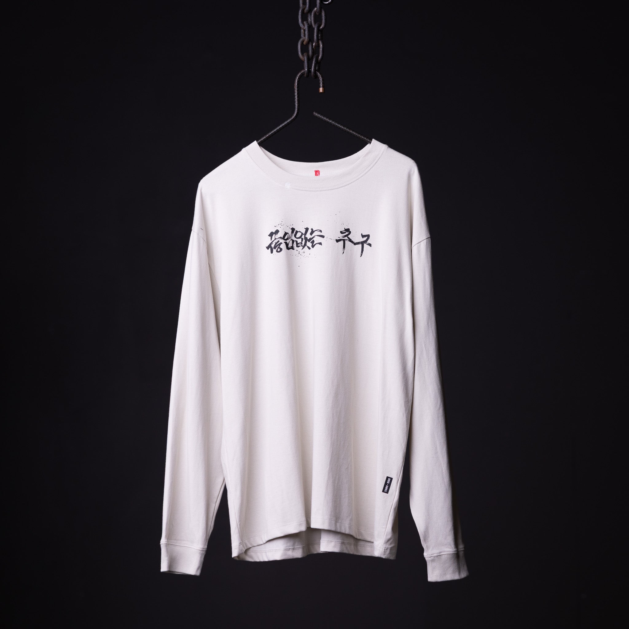 SP'23 Graphic Long Sleeve in white, displayed on hanger against dark background