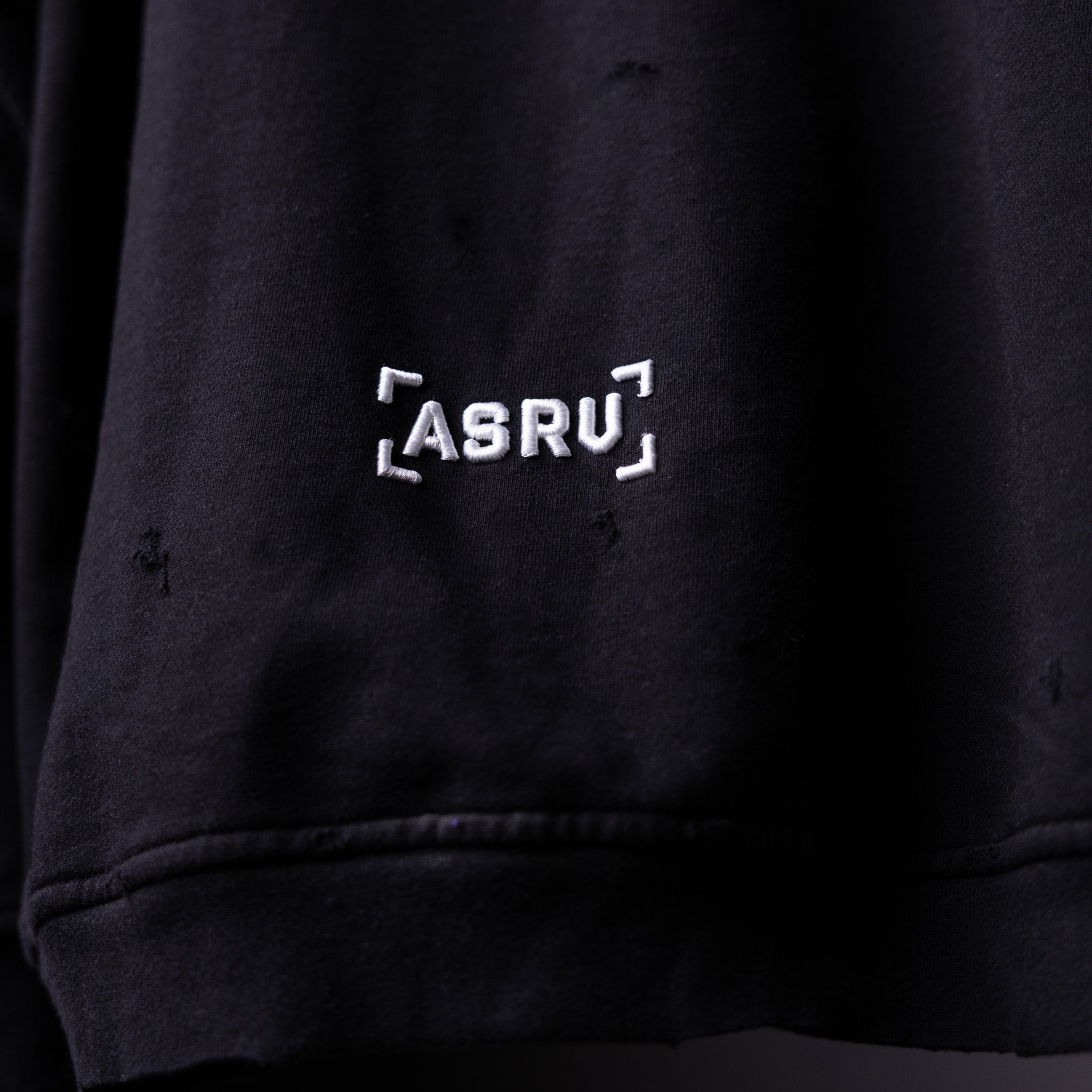 FA'20 Distressed Hoodie in black, close-up detail of ASRU logo embroidery on chest