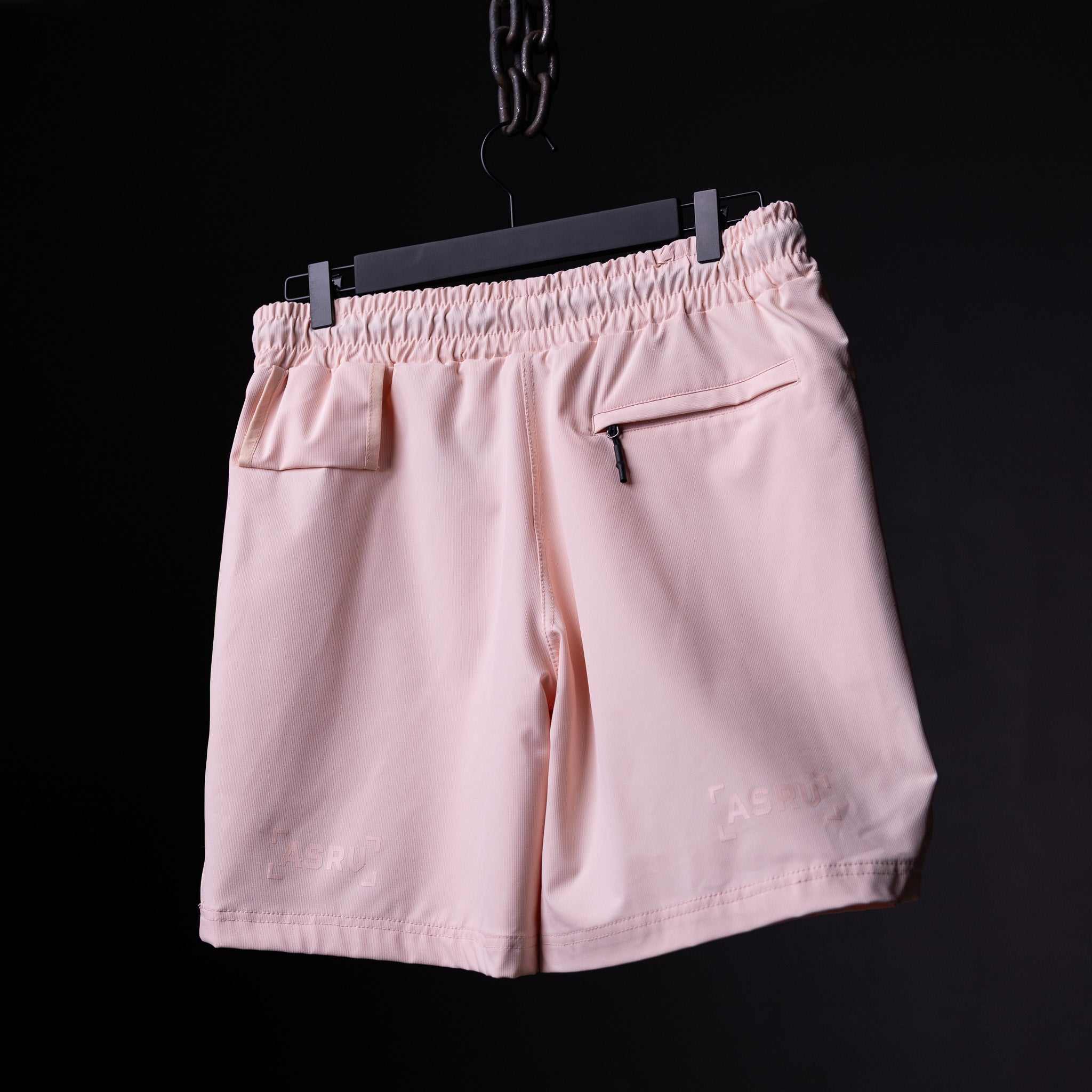 flatlay of pink Coastal Training Short on black hanger against dark background, back view