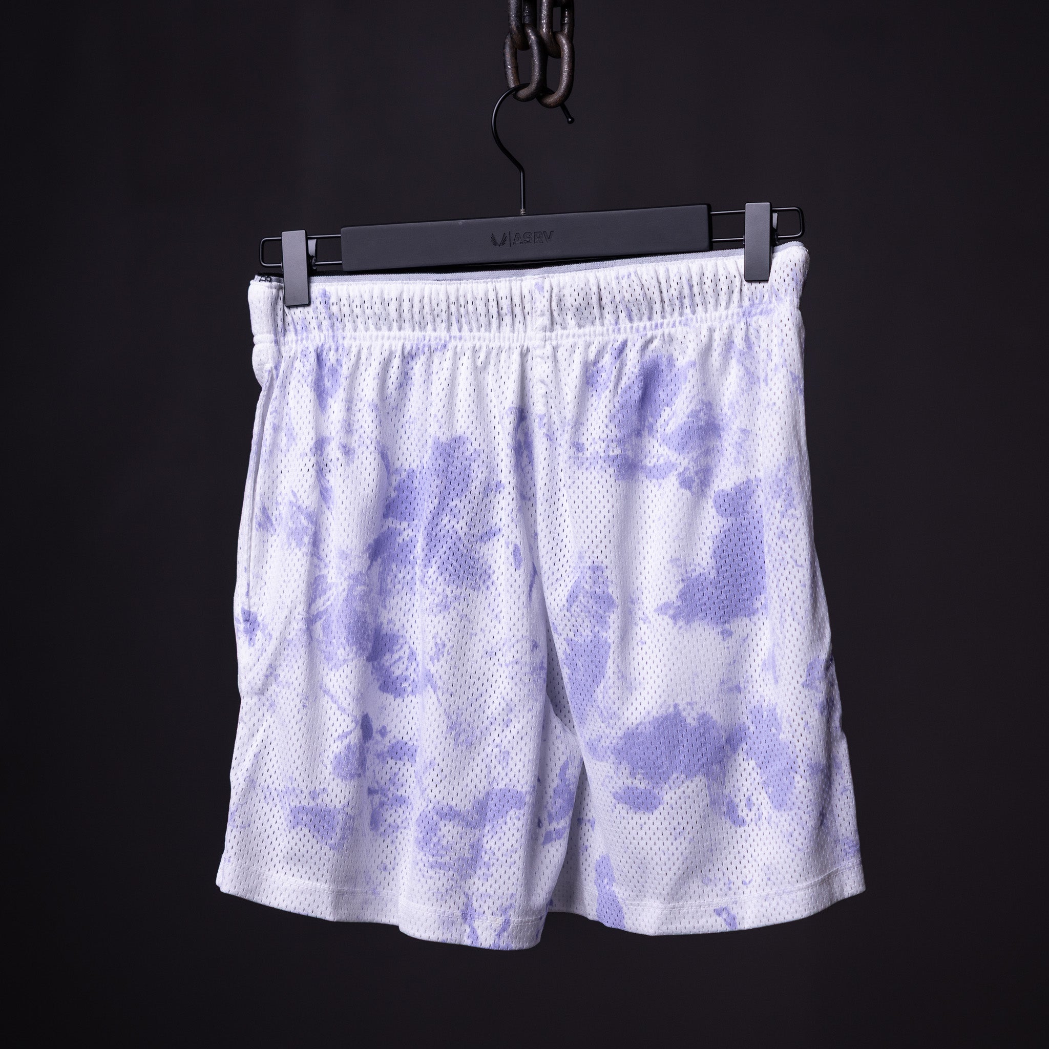 flatlay SM'22 Tie Dye Painted Short in purple and white, hung on black hanger against dark background
