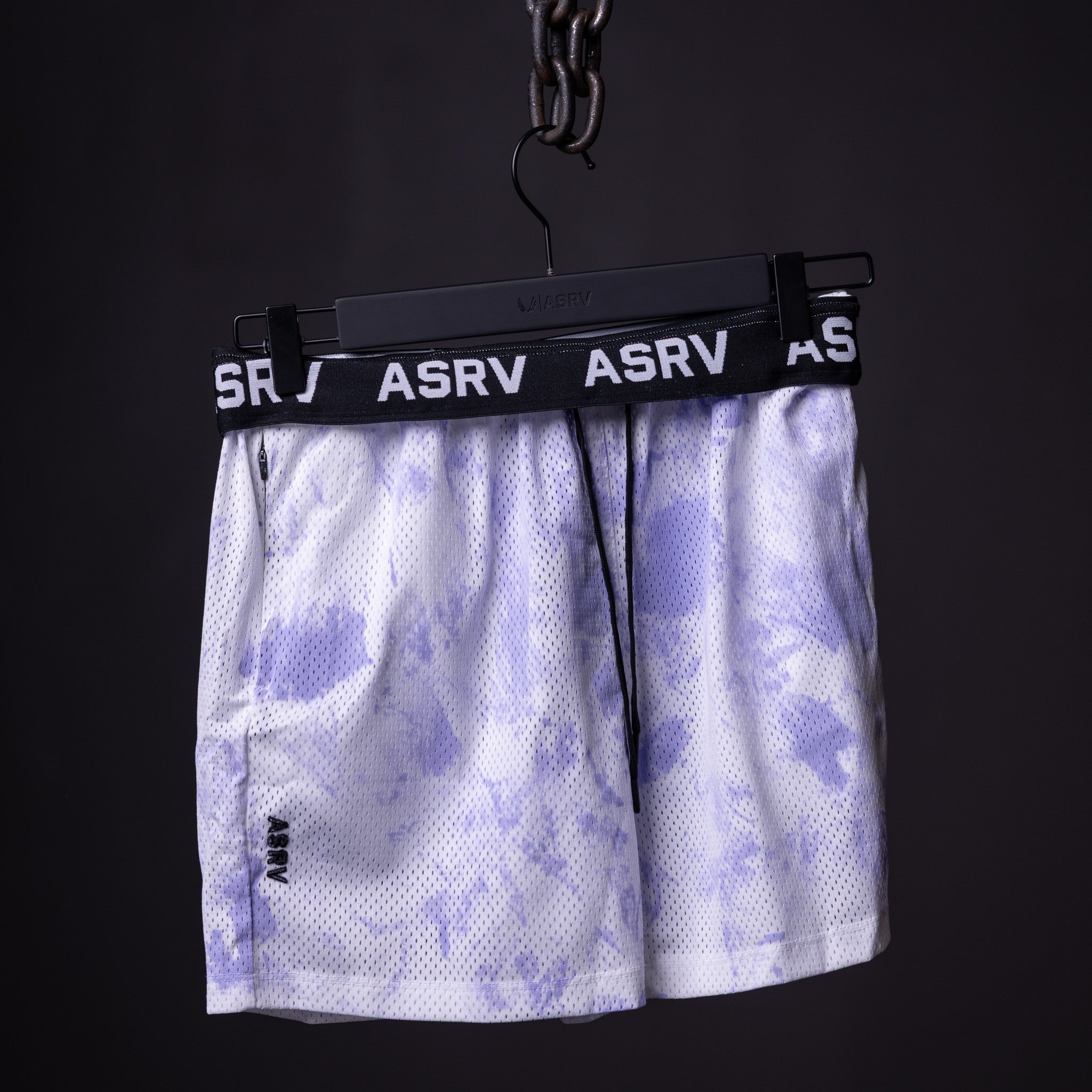 SM'22 Tie Dye Painted Shorts in purple and white, hanging on display