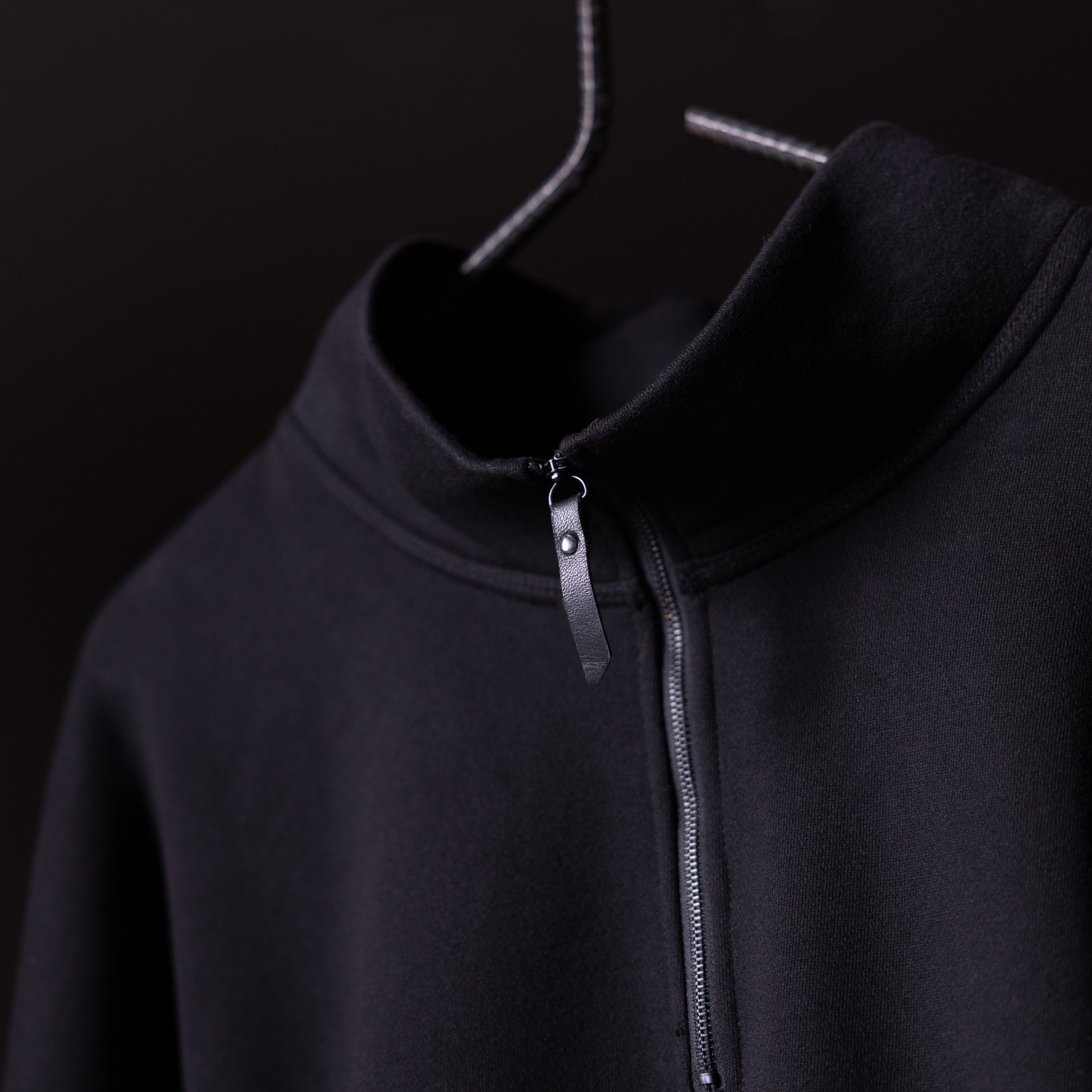 Black quarter zip hoodie on hanger, showing front neckline and zipper detail