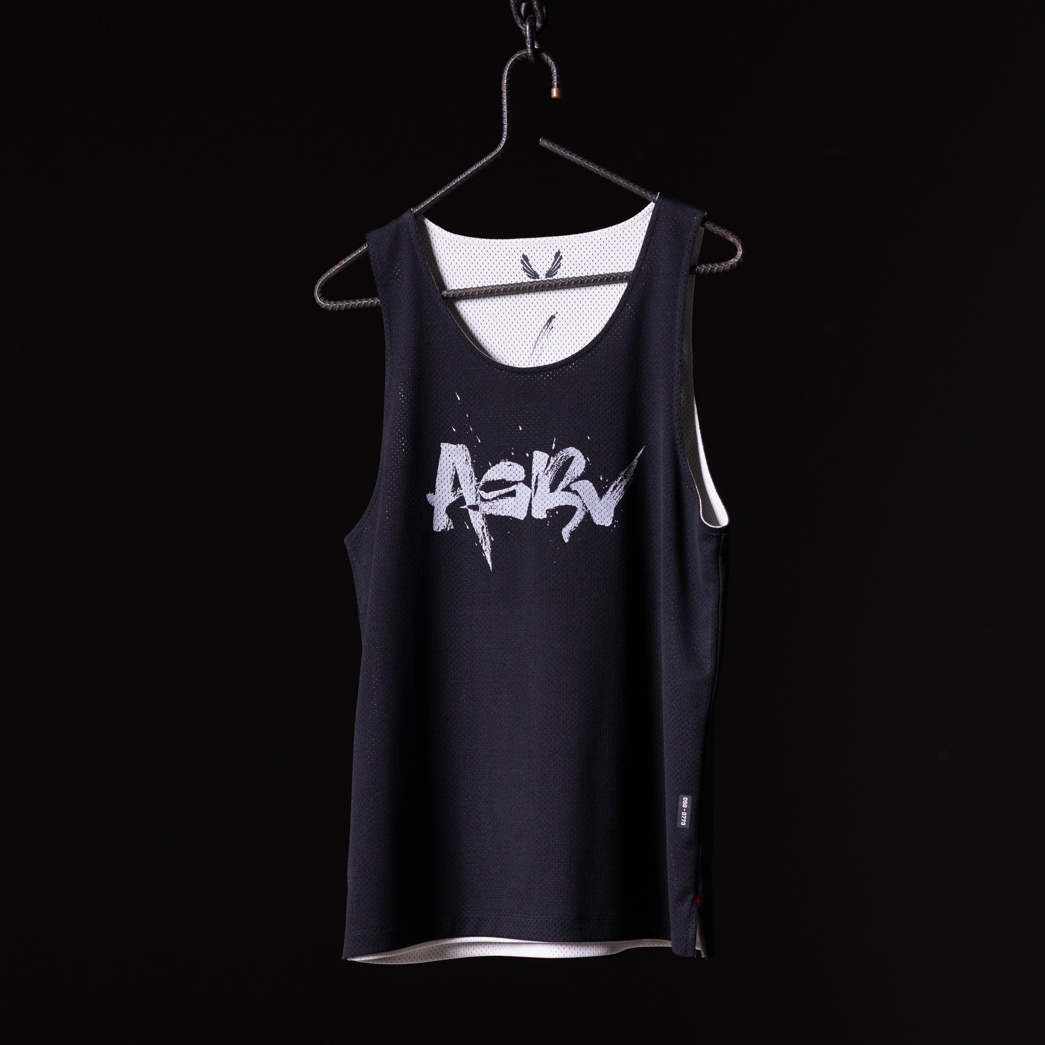 SM'23 Mesh Reversible Pinnie in black with white mesh lining, displayed on hanger