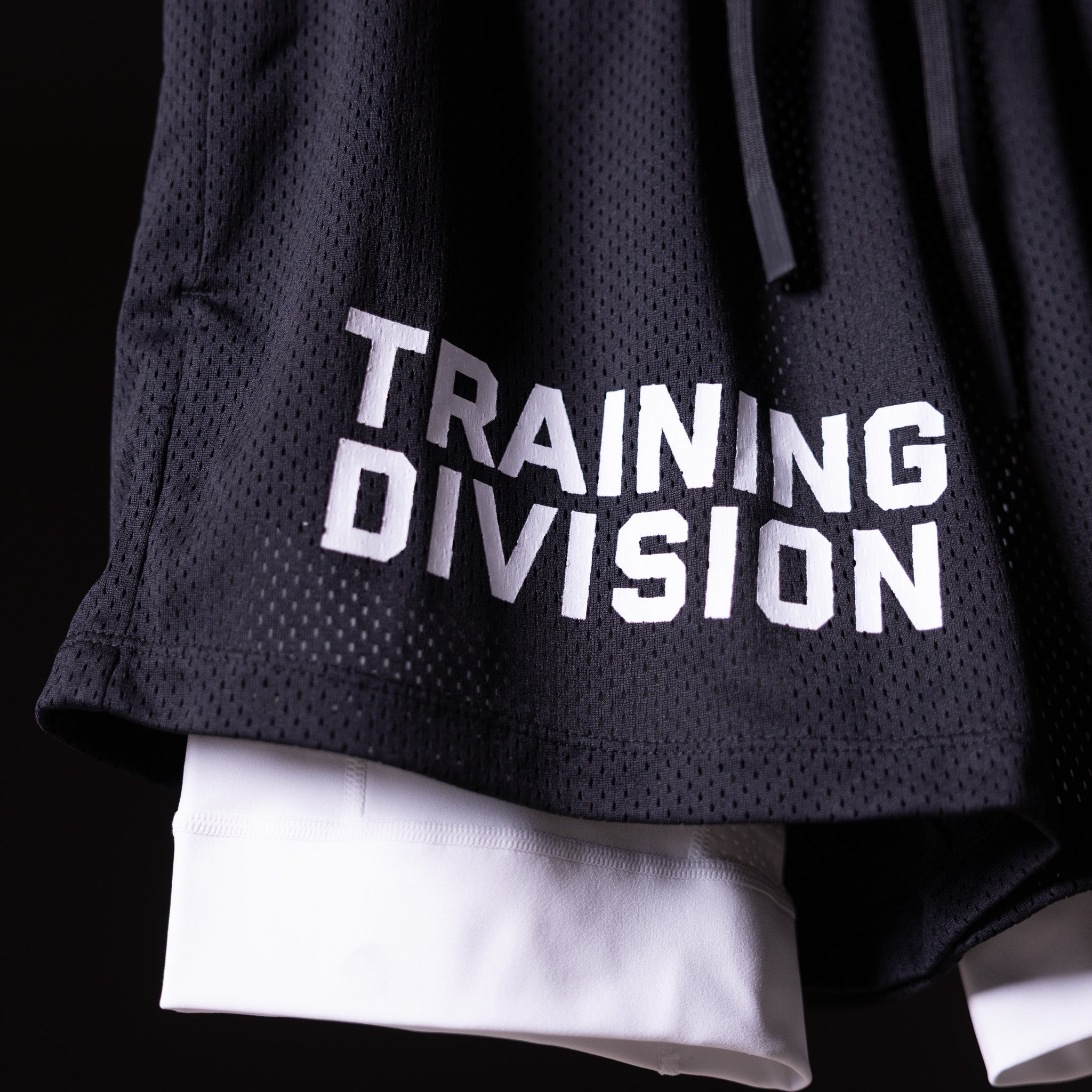 FA'23 Training Division mesh shorts in black worn by model, showing white underlay and embroidered logo detail