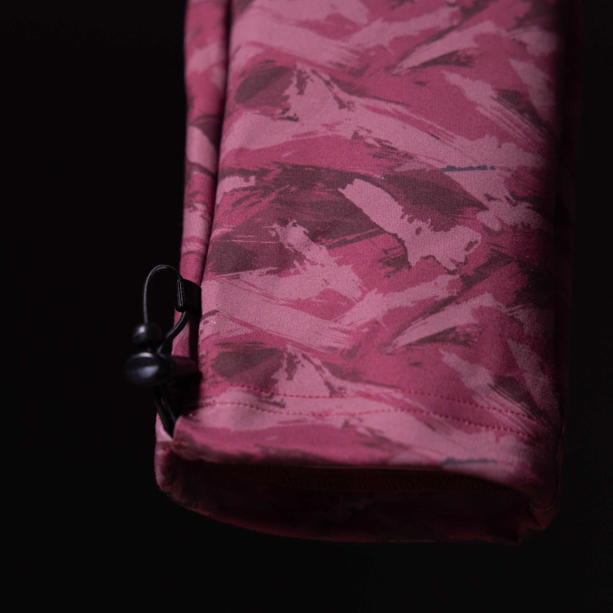 Brushed camo cargo jogger in burgundy, held against dark background detail shot