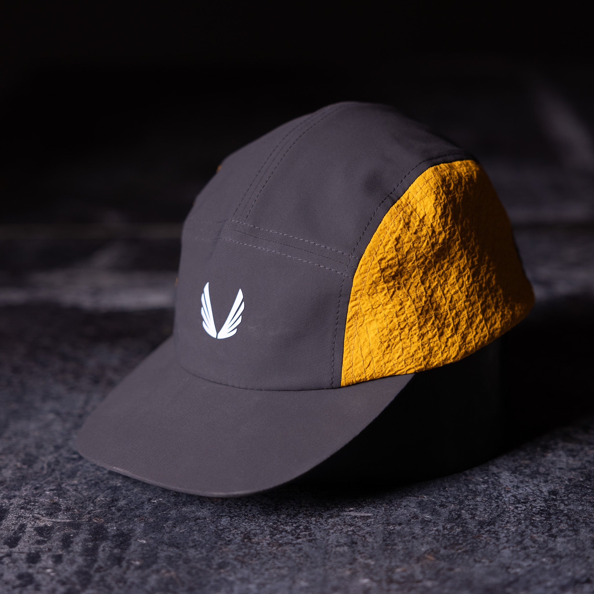 Flatlay of Two Tone 5 Panel Hat in charcoal grey and gold, side view