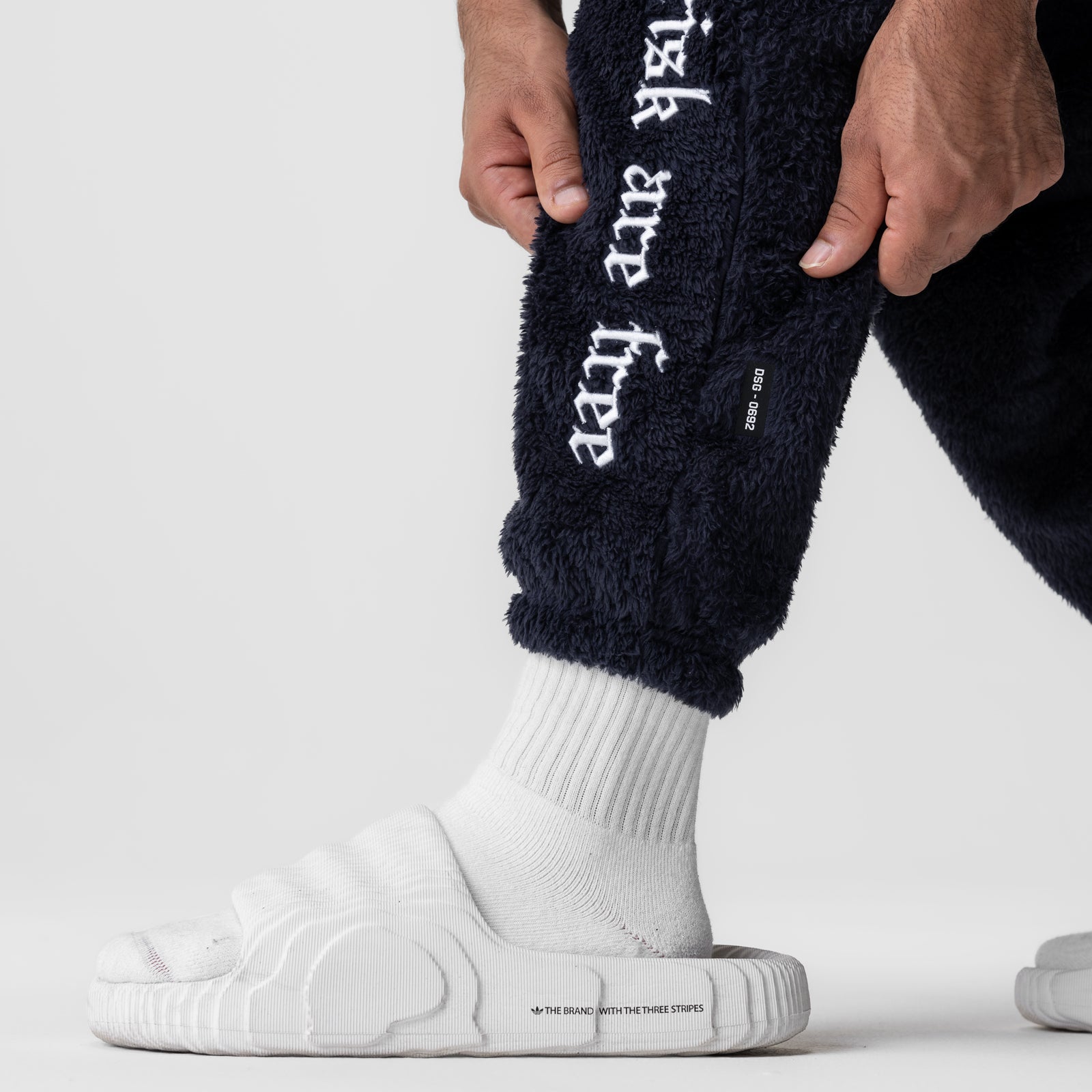 Sherpa Recovery Sweats in navy worn with white socks and slides, leg detail view