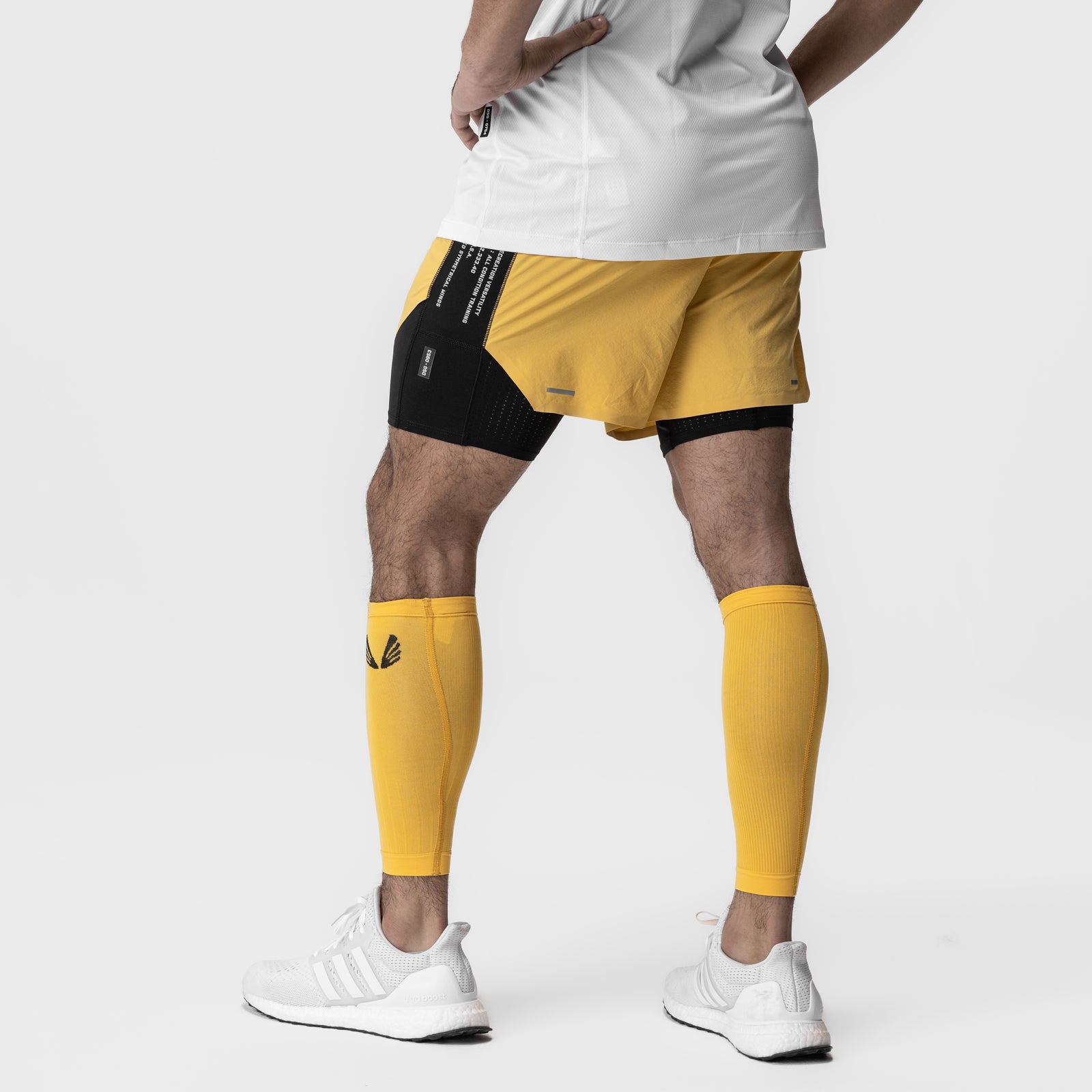 Body-Mapped Calf Sleeve in amber yellow worn on model's legs with shorts and white sneakers