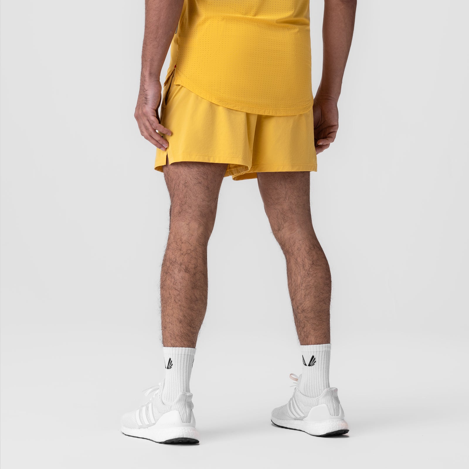 Aerotex™ 5" Training Short in amber yellow, modeled from behind with white socks and sneakers