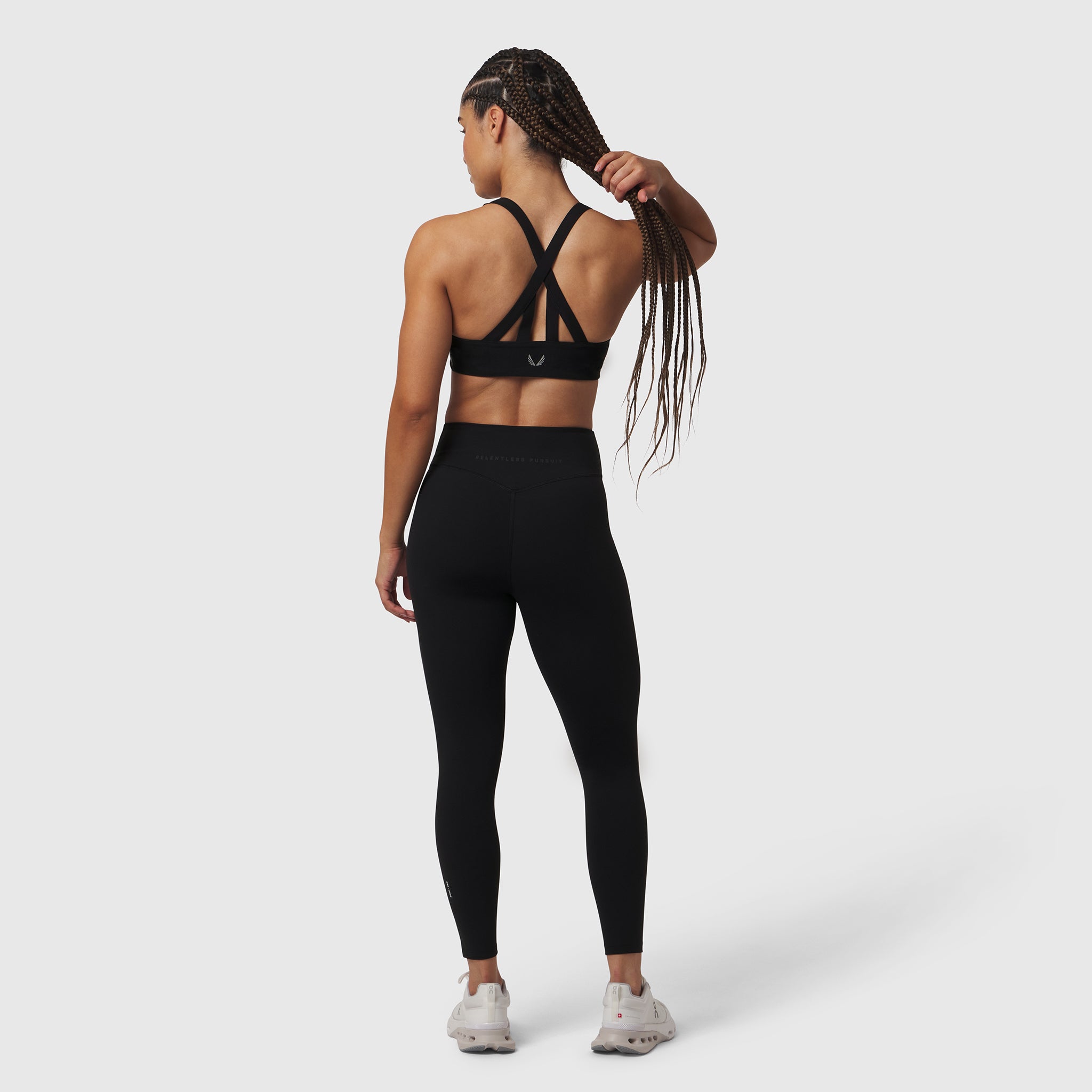 Black LYCRA® ADAPTIV legging worn by model, rear view, with strappy sports bra