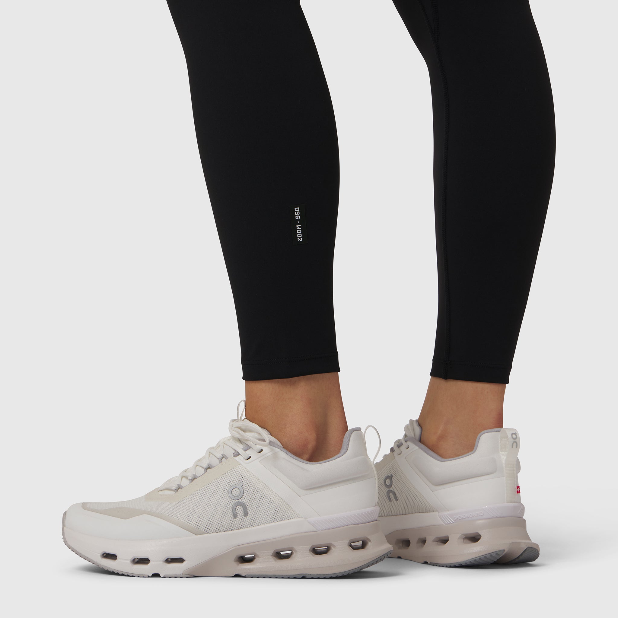 W002 LYCRA® ADAPTIV Legging in black, worn with white sneakers, side view