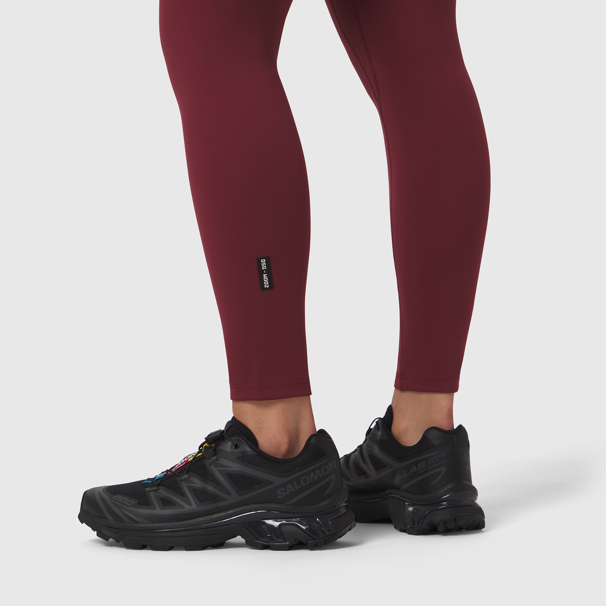 W002 LYCRA® ADAPTIV Legging in crimson worn with black sneakers, lower body view