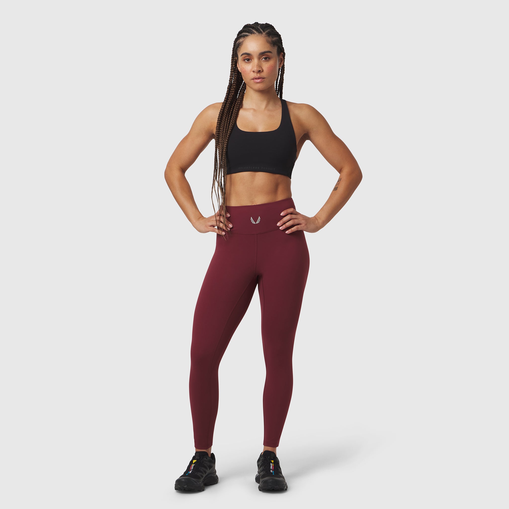 W002 LYCRA® ADAPTIV Legging in crimson, worn with black sports bra and black sneakers